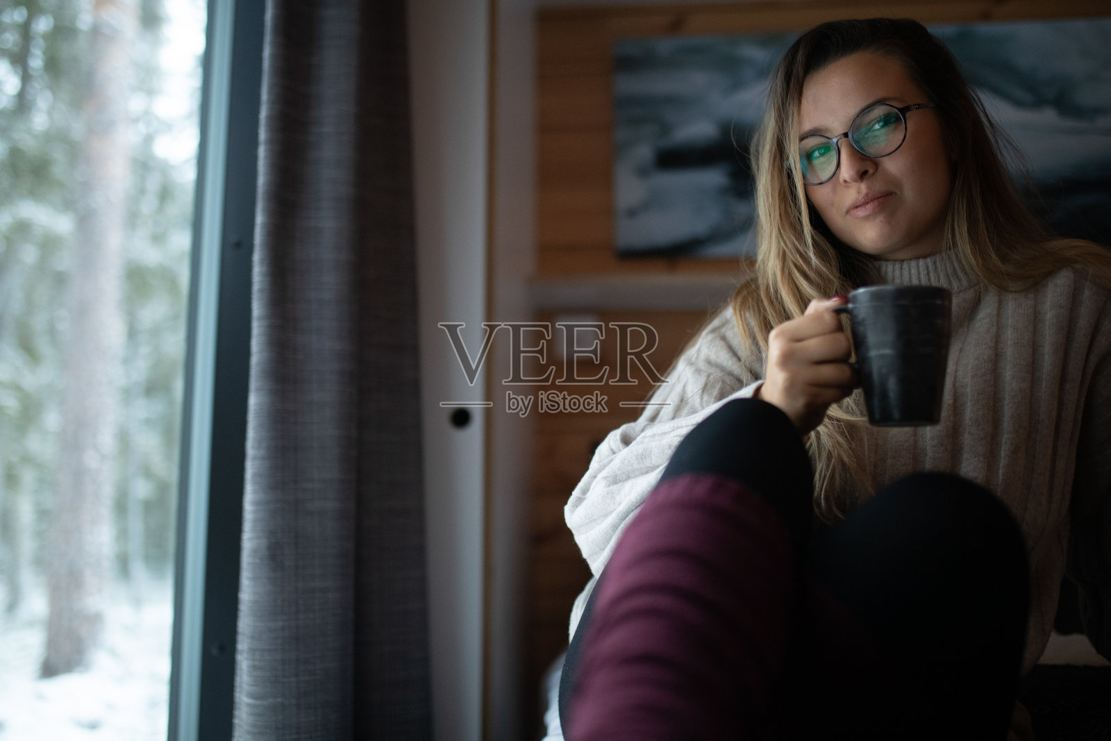 这个女人坐在床上，手里拿着一杯咖啡照片摄影图片