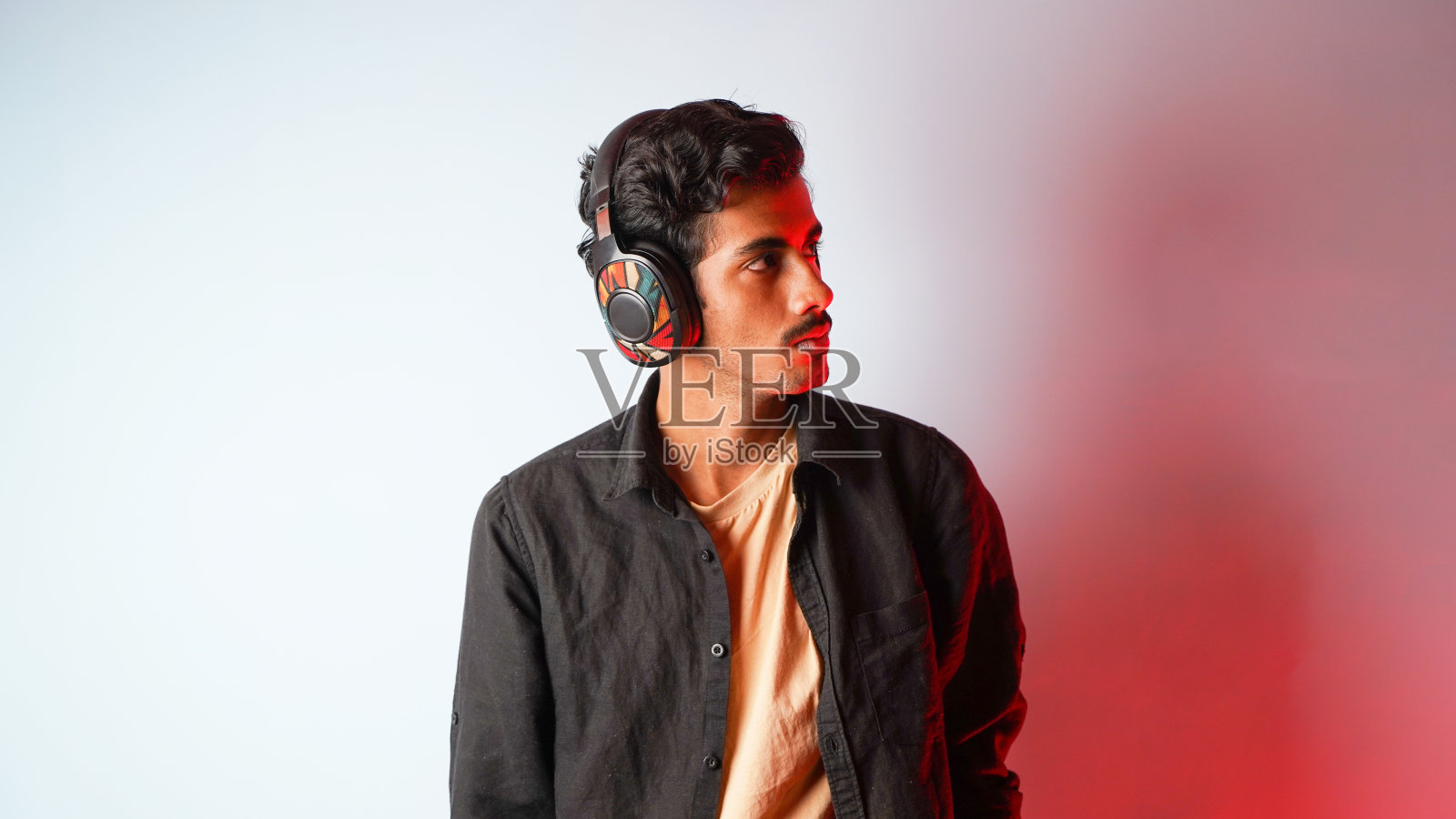 年轻人听音乐孤立的颜色背景，放松和享受音乐，耳机音乐概念照片摄影图片