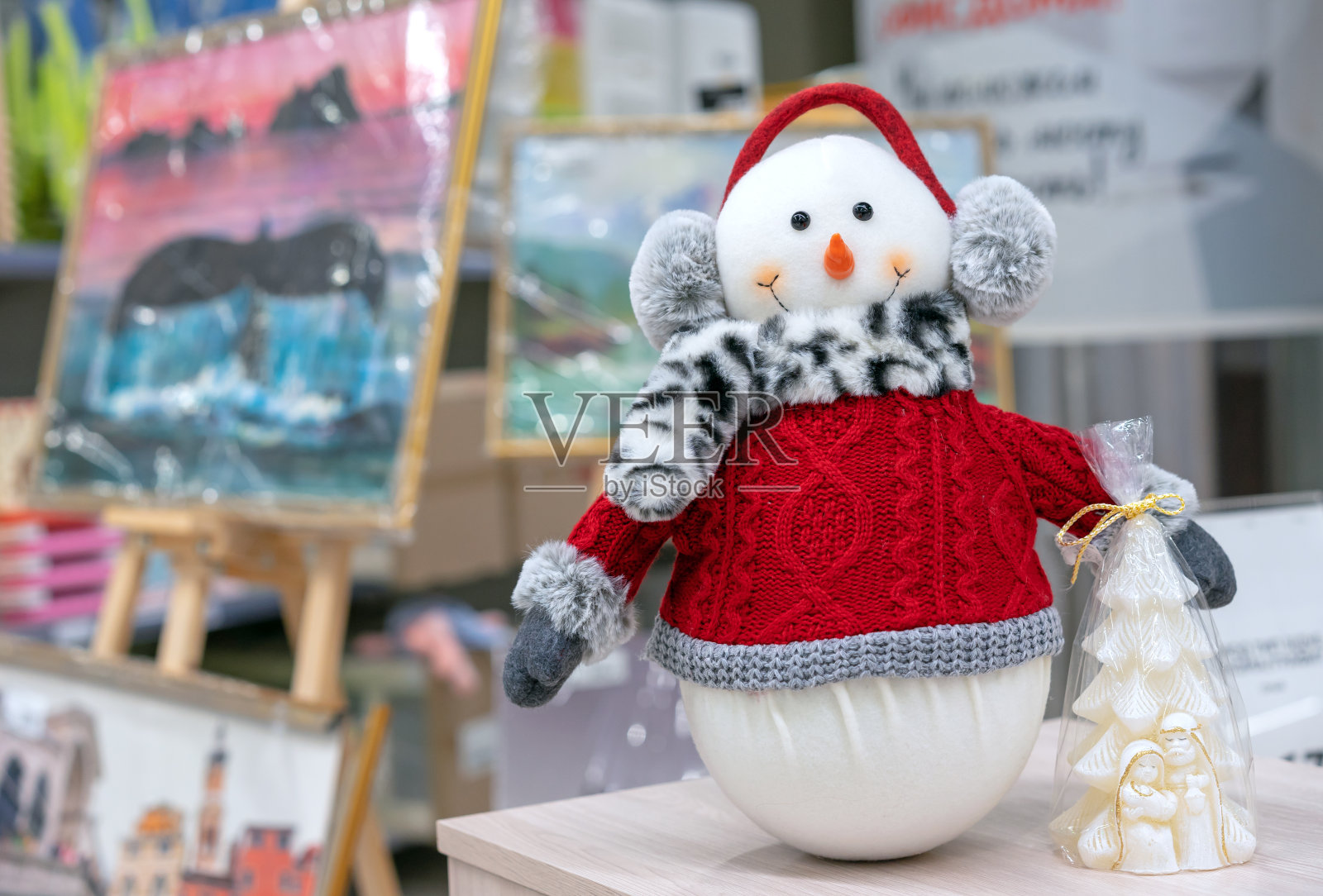 雪人穿着红色针织毛衣，围巾和帽子耳机。照片摄影图片