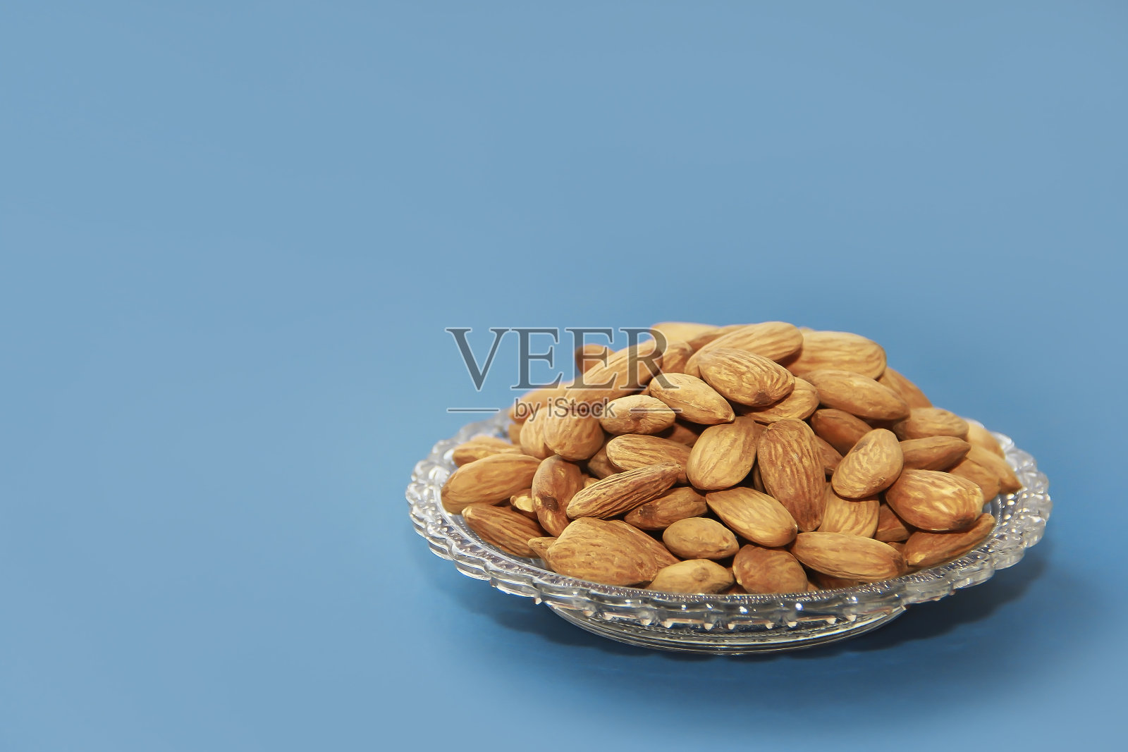 小粒天然的棕色杏仁放在装饰玻璃盘子里照片摄影图片