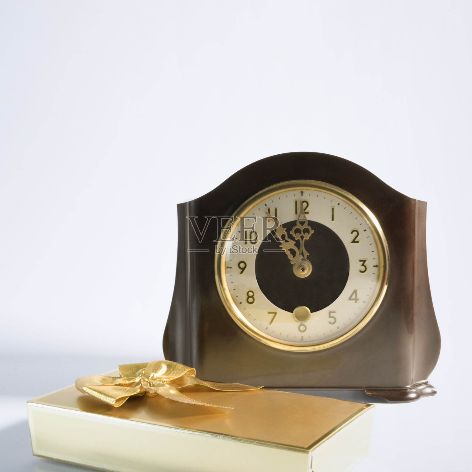 礼物时间到了。经典的桌子时钟和礼品包裹在金蝴蝶结。在白色的背景上。广场的格式照片摄影图片