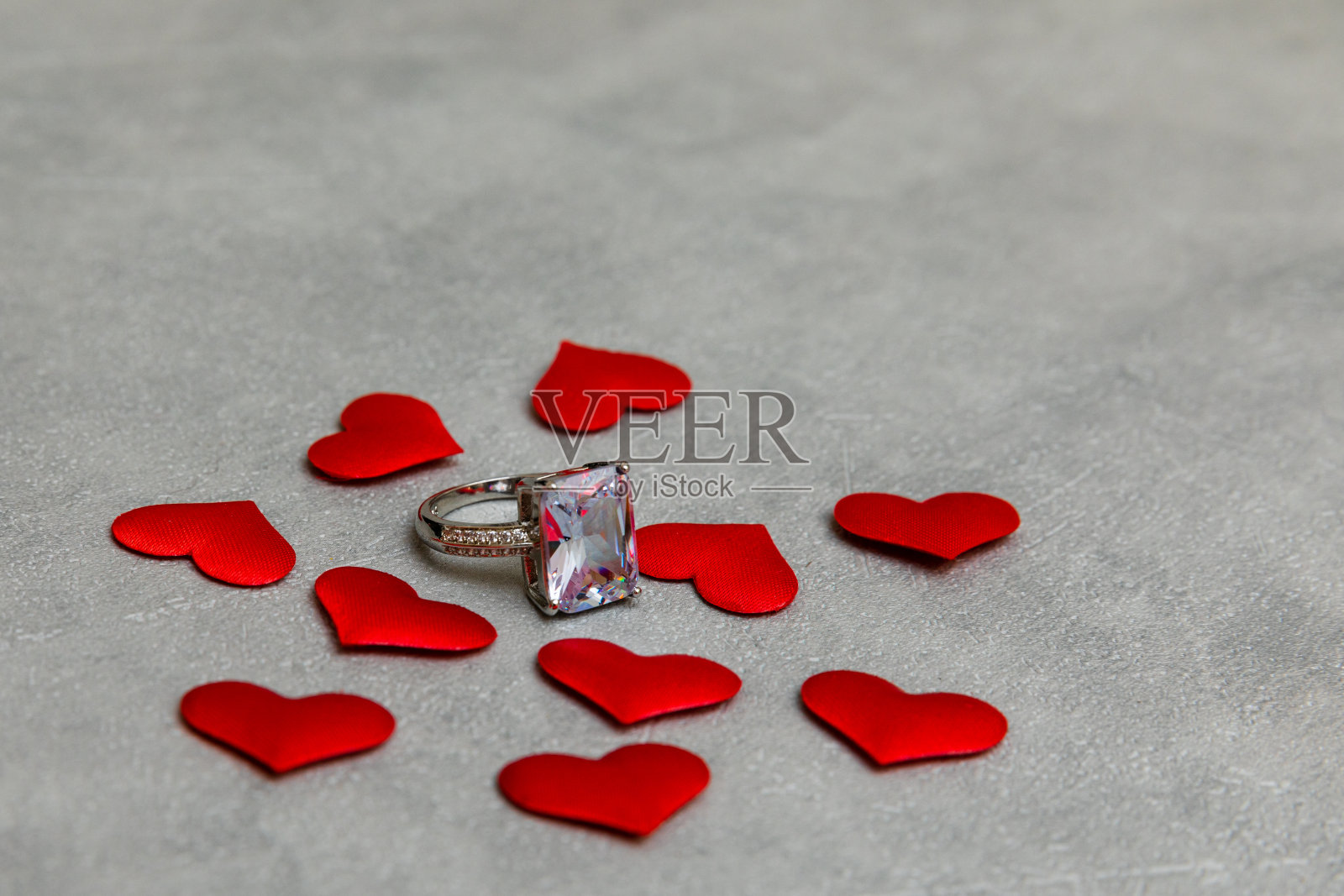 嫁给我好吗?结婚戒指许多红心混凝土石头灰色背景。订婚求婚婚礼概念。情人节明信片。情人节的横幅。照片摄影图片