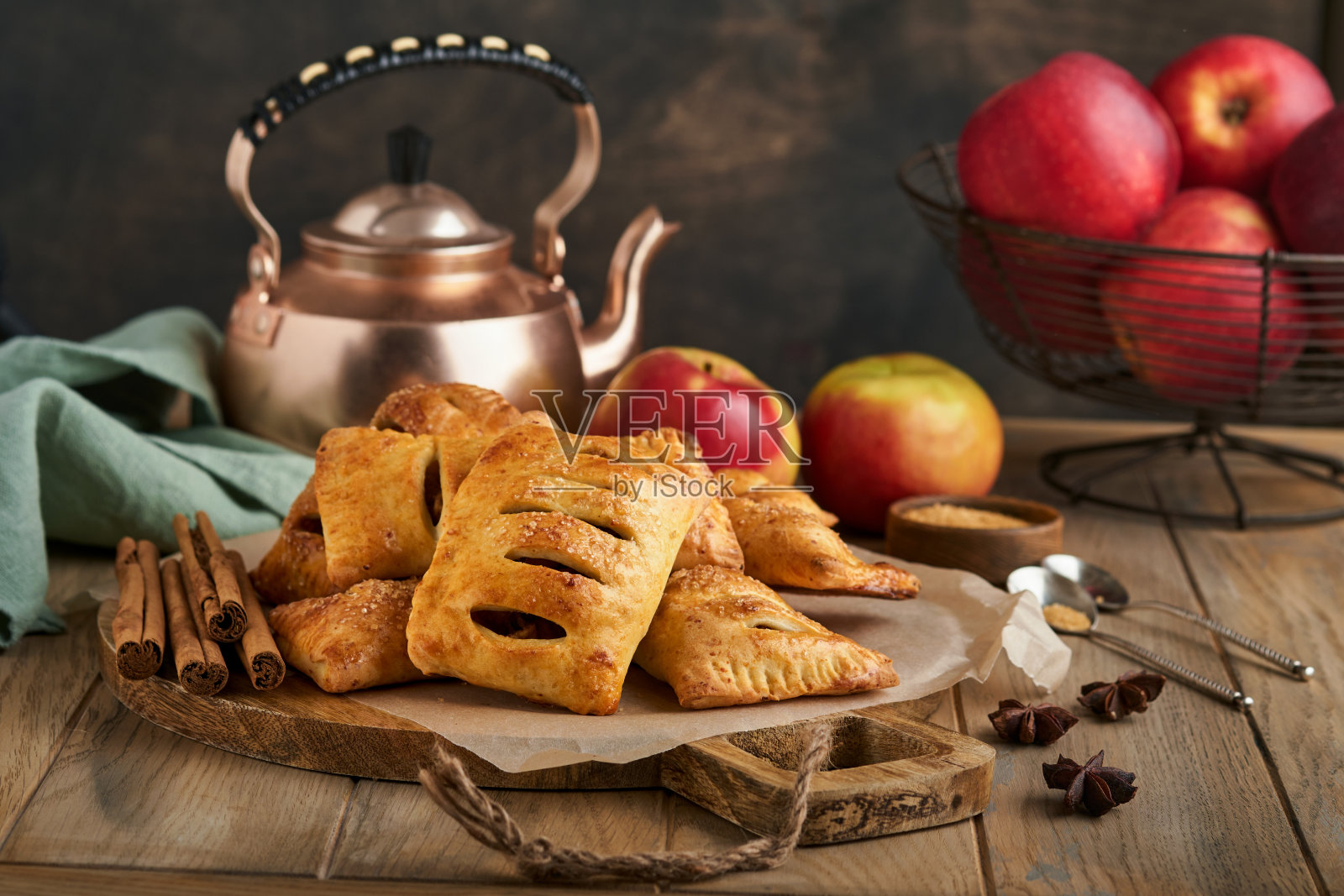 手派。小酥皮或手馅饼填满苹果和撒糖粉在木盘。自制的馅饼点心与皮的早餐乡村照片。副本的空间。照片摄影图片