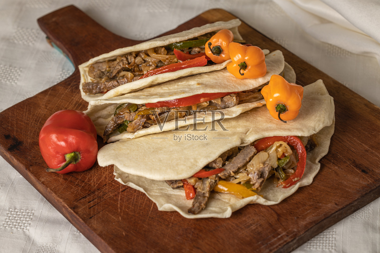 墨西哥卷饼，典型的墨西哥食物，牛肉，蔬菜和辣椒放在木板上。照片摄影图片