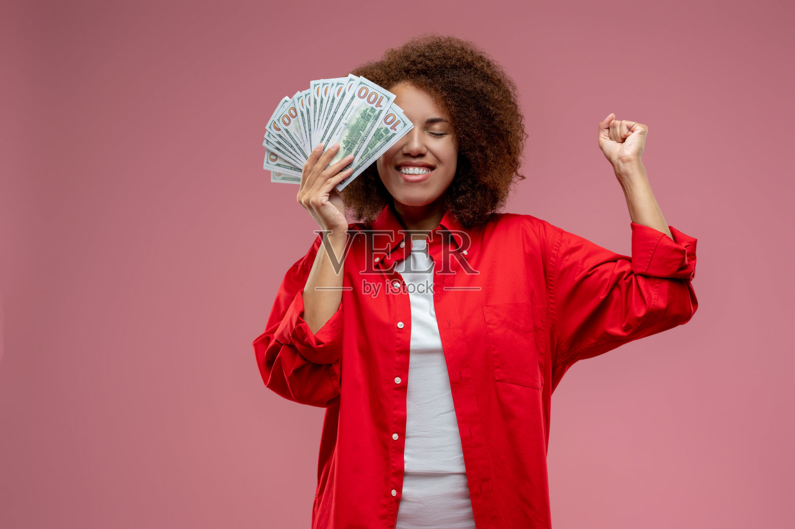 漂亮的卷发女人在红色夹克手里拿着钱照片摄影图片