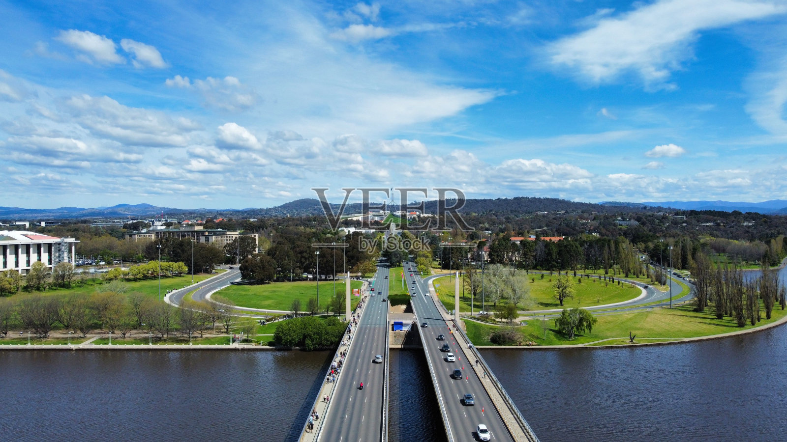 鸟瞰公园附近桥上的高速公路和蓝色多云天空下的湖泊照片摄影图片