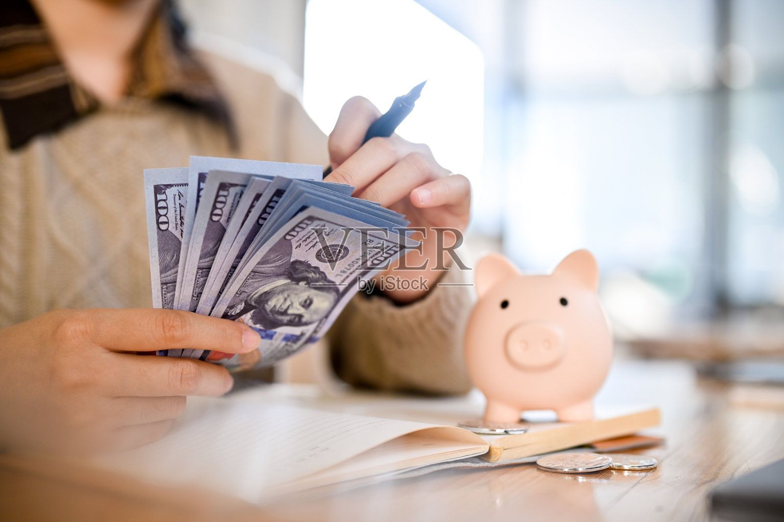 一名妇女拿着一箱美元钞票，清点和核对她的现金。照片摄影图片