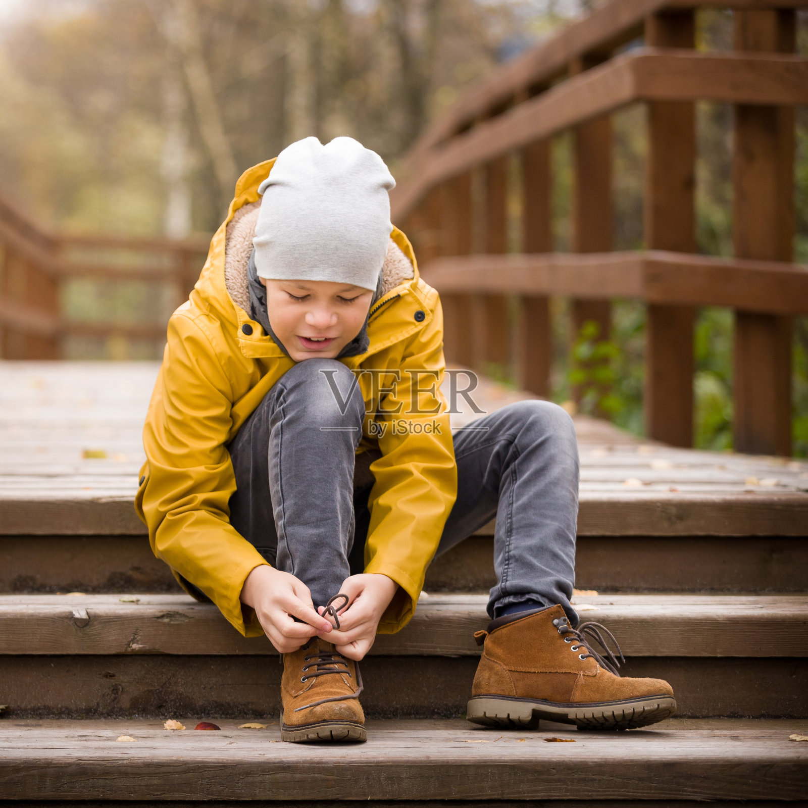 在一个寒冷的秋日，可爱的孩子系着鞋带在城市公园散步。男孩在户外照片摄影图片