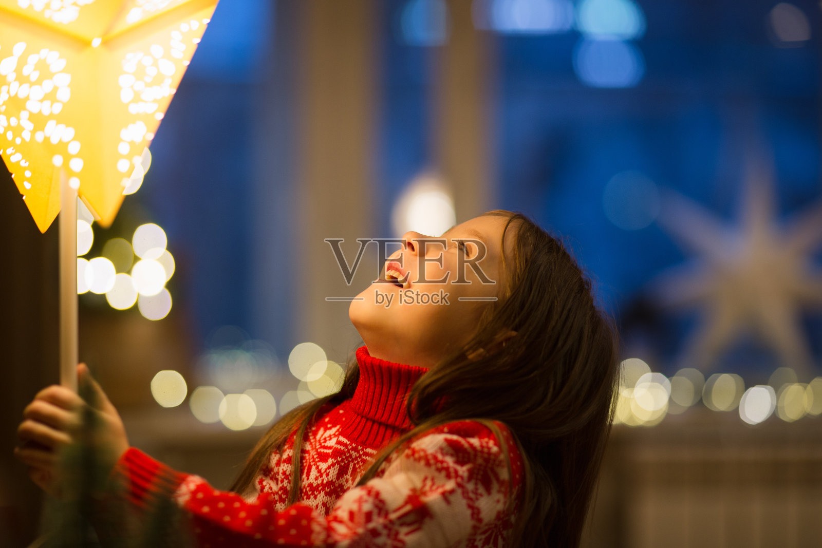 孩子在家里为圣诞节的装饰品——星星形状的灯而高兴照片摄影图片