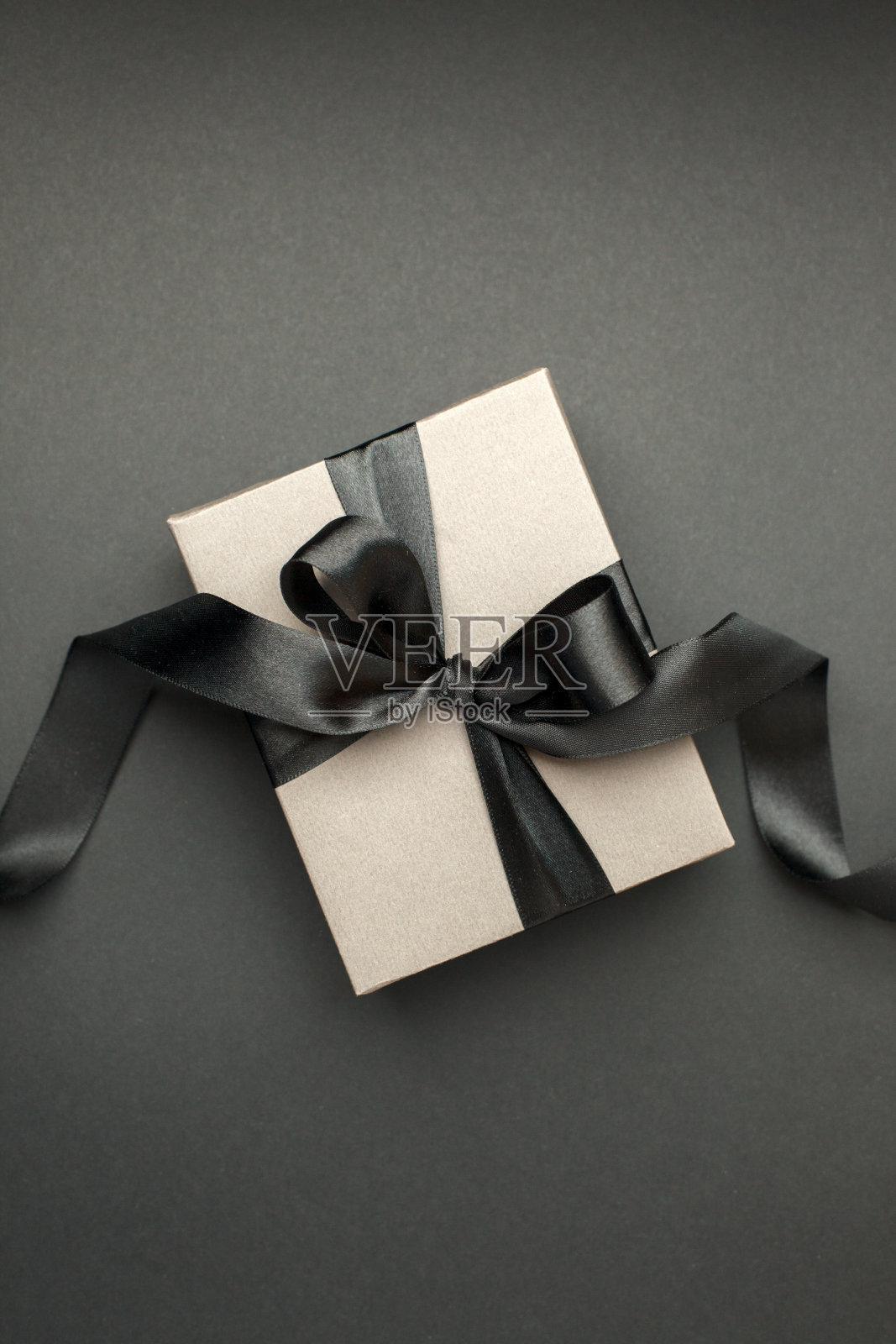 工艺礼盒以深色为背景，饰以有质感的蝴蝶结，营造浪漫奢华的氛围。生日，周年纪念礼物，礼品明信片，横幅，传单，邀请，代金券照片摄影图片