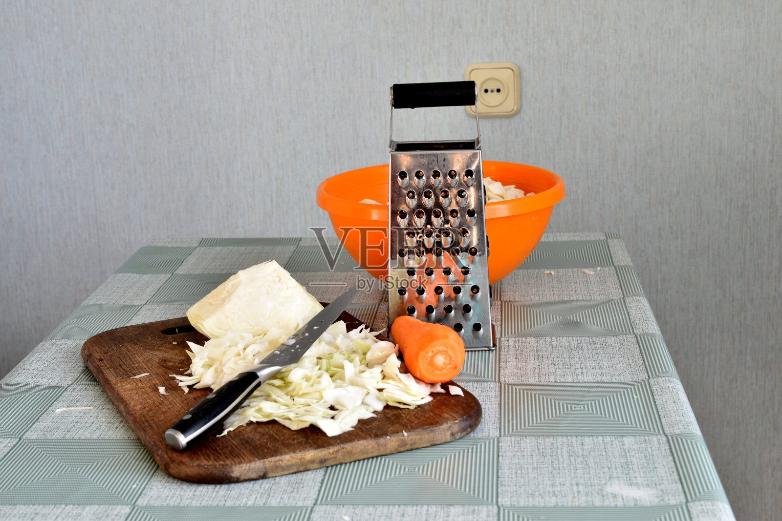 厨房里的桌子，砧板，刨丝器，刀，切碎的卷心菜。照片摄影图片