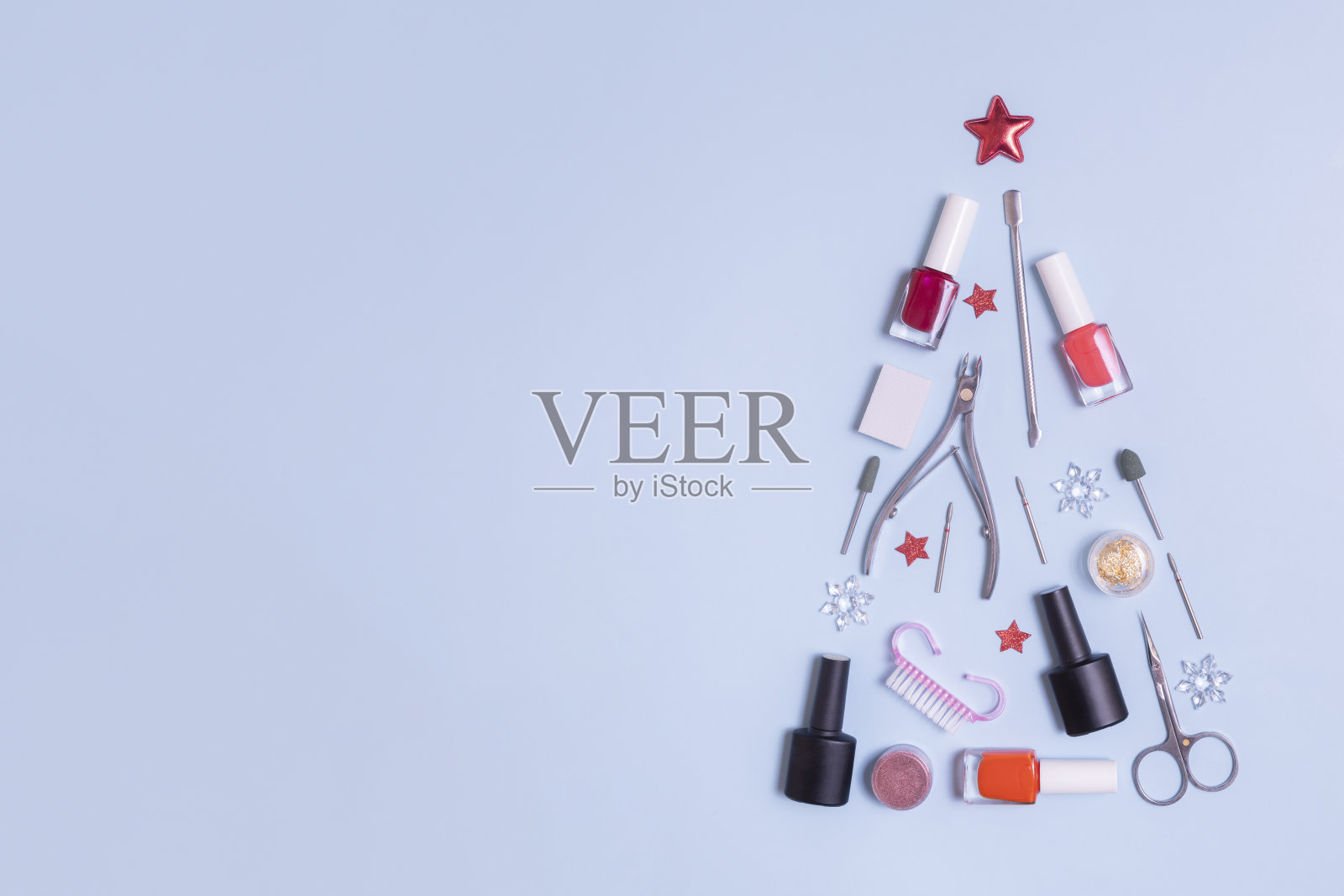 美甲工具和指甲油被布置成圣诞树的形状，蓝色背景上有复制空间照片摄影图片