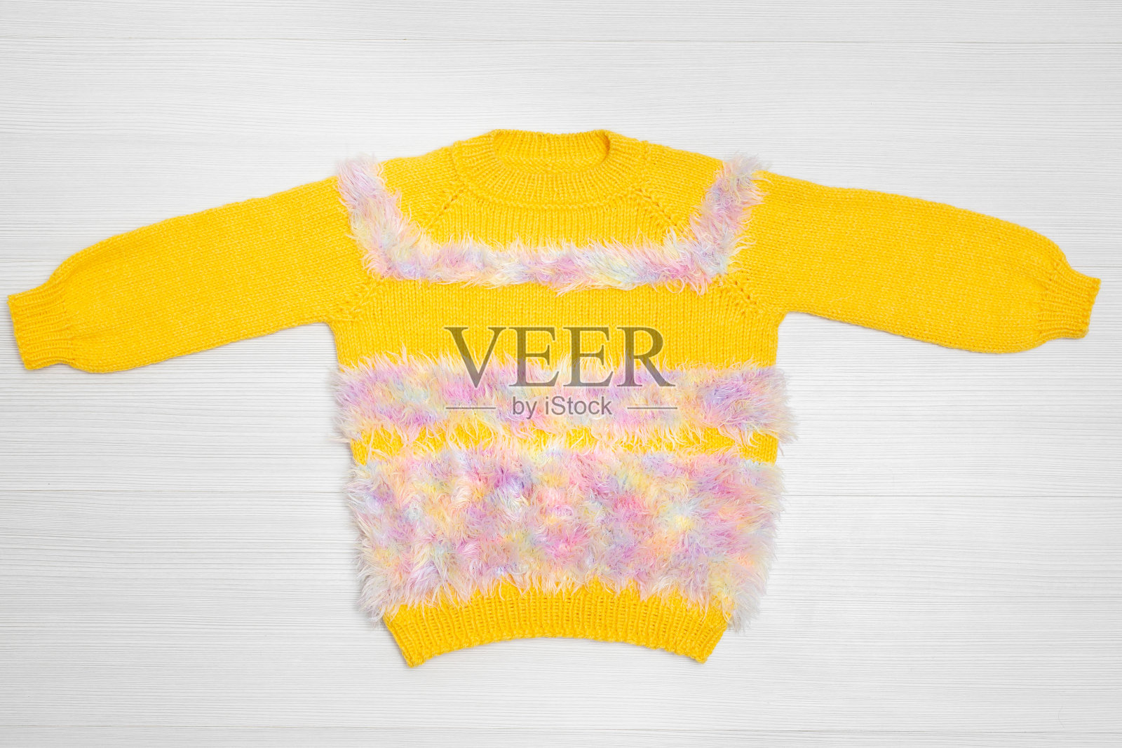 白色背景上温暖的儿童黄色毛衣，俯视图。细节照片摄影图片