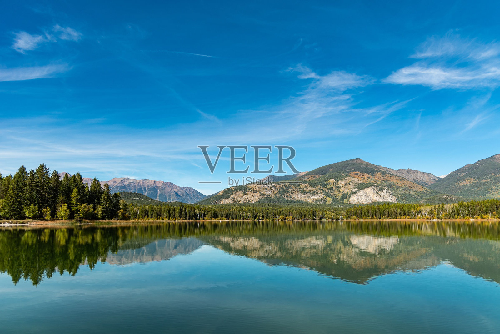 树木和落基山脉倒映在宁静的湖面上照片摄影图片