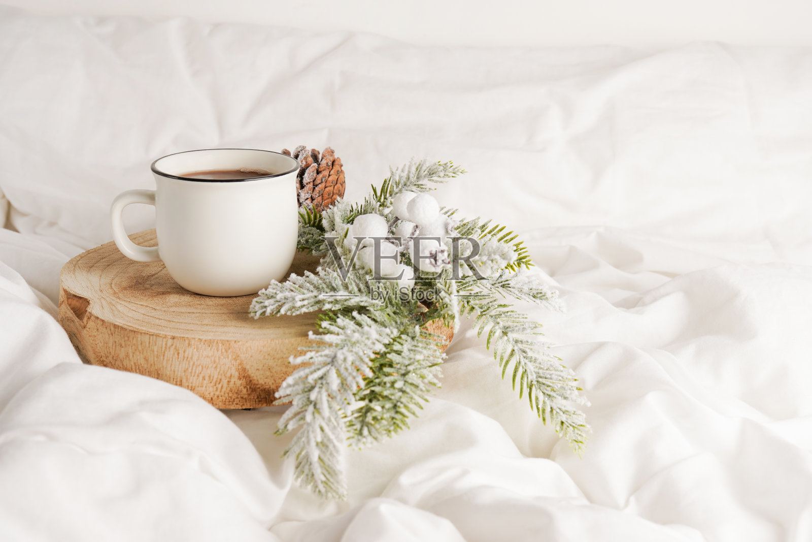 咖啡杯放在木头上，白色的床上有圣诞装饰。在床上吃早餐。冬天的早晨照片摄影图片