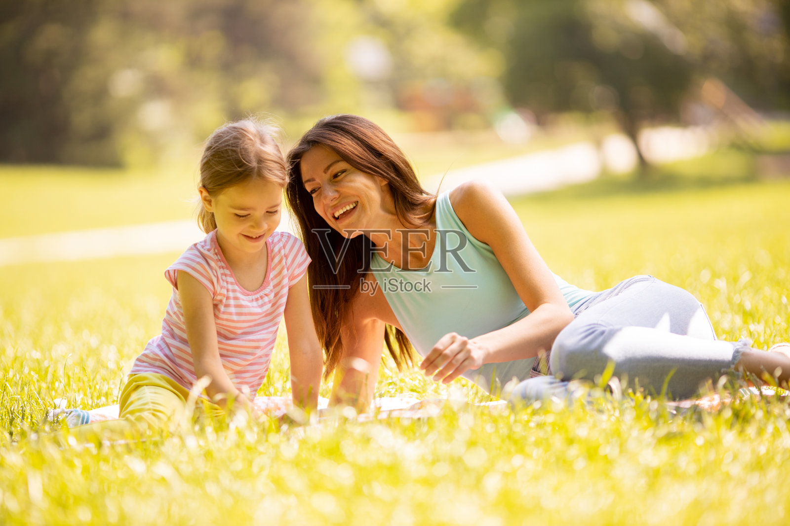 在一个阳光明媚的日子里，妈妈带着小女儿在公园里玩照片摄影图片