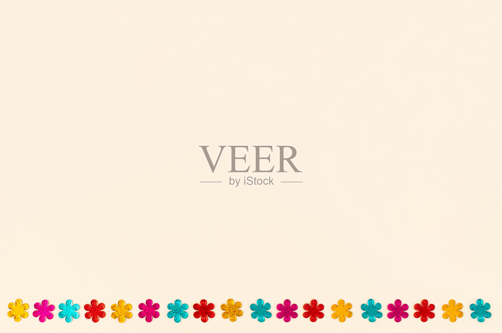 在白色背景上排列的多色花朵形状的亮片。照片摄影图片