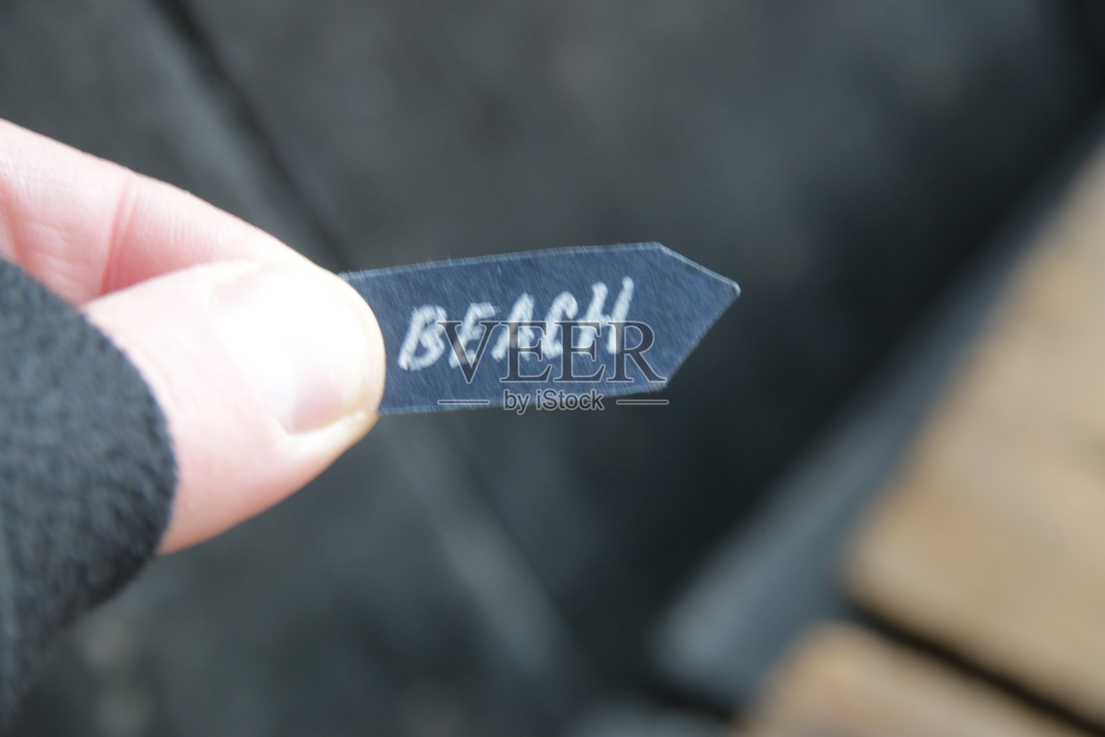 海滩上的想法。一只手握着写有“海滩”字样的指针。照片摄影图片