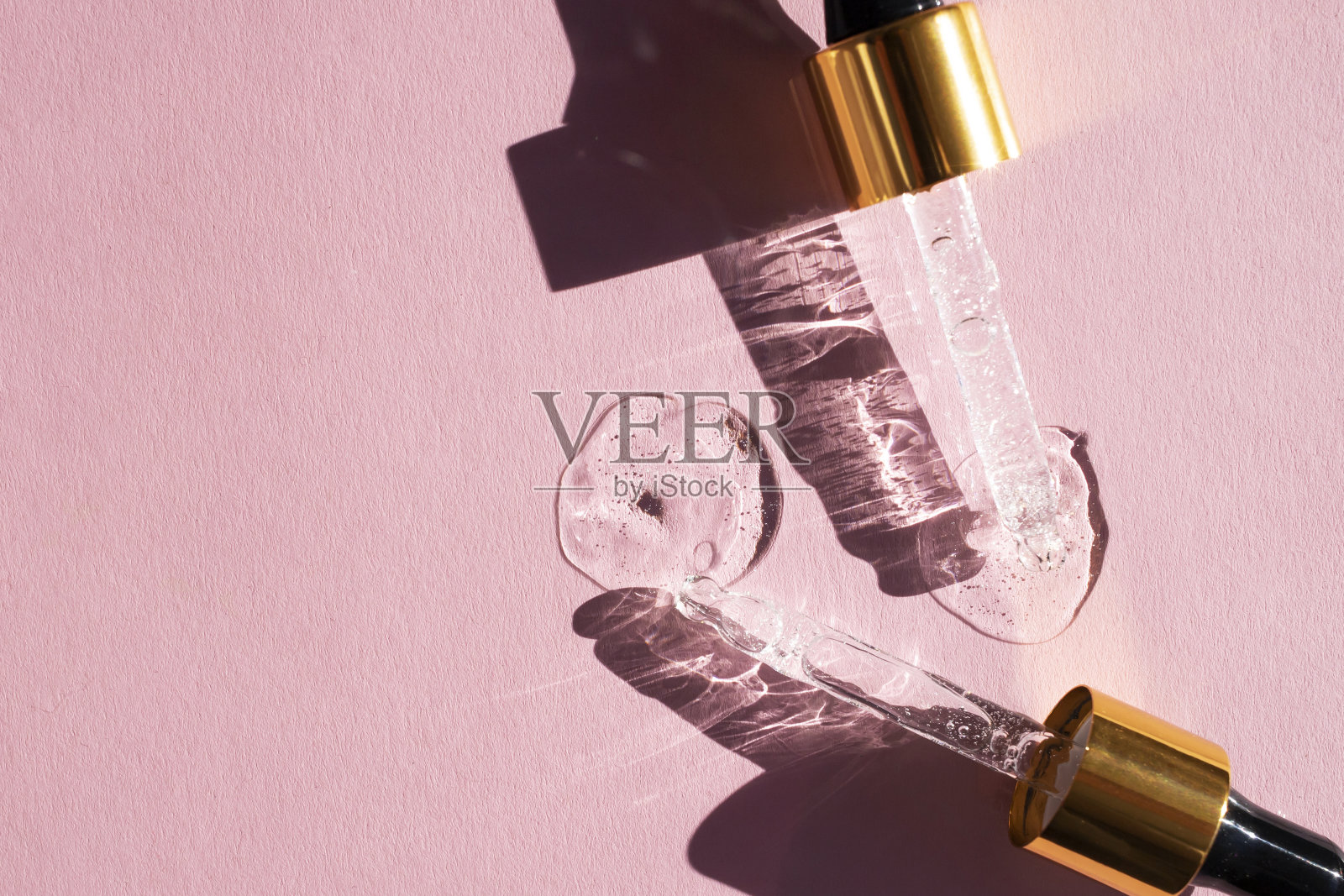 透明的玻璃移液管和粉色背景上的精华滴。俯视图，放置文本。照片摄影图片