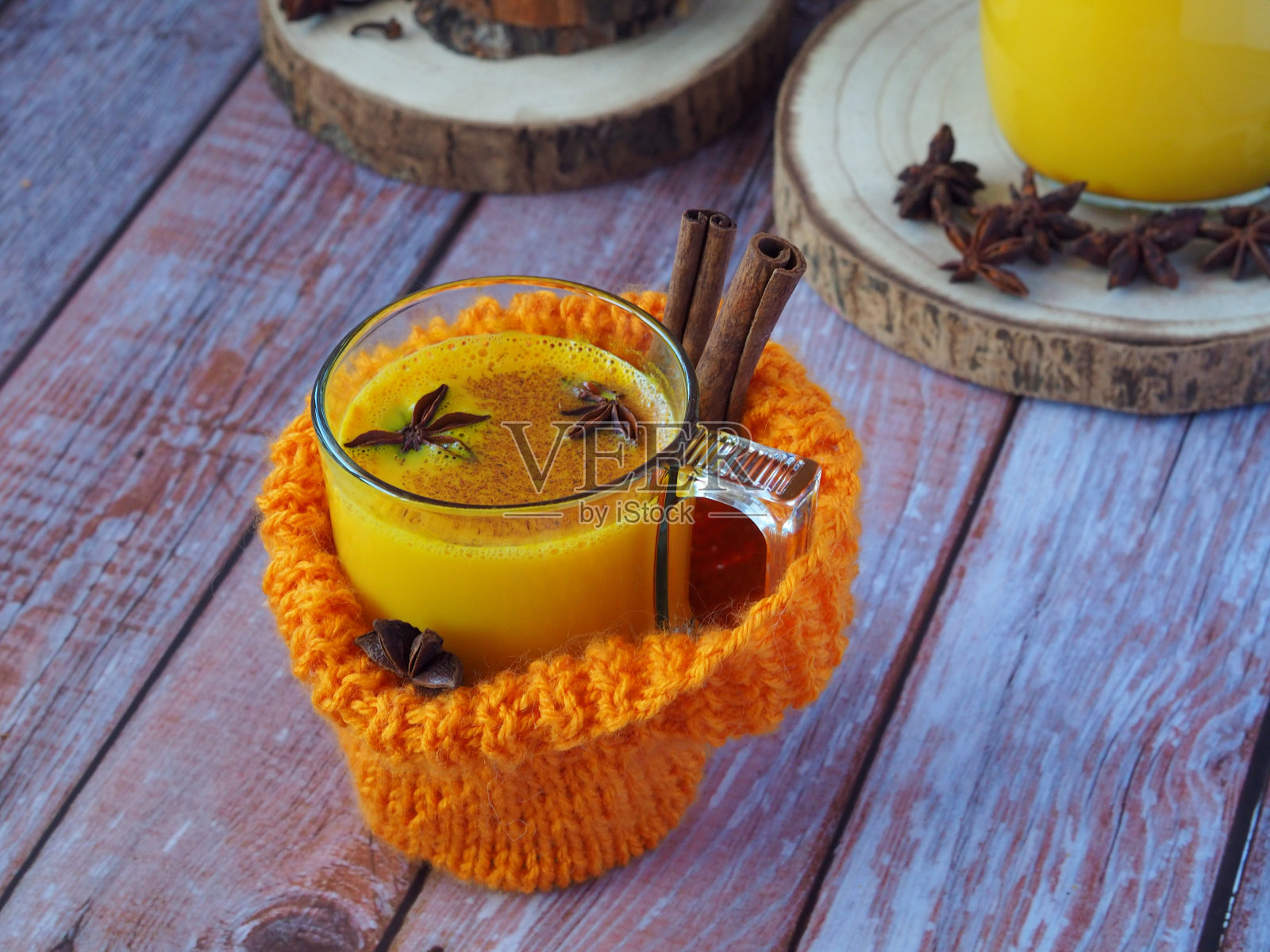 木桌上摆着一只针织羊毛盒，里面装着一杯金黄色的热牛奶照片摄影图片