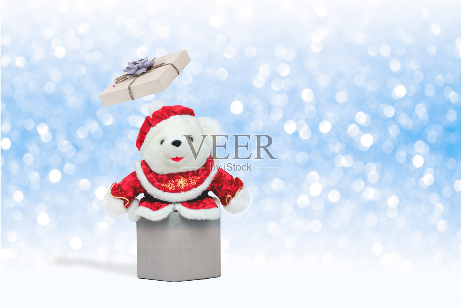 白色的泰迪熊在圣诞服装出现从打开礼品盒上的雪花装饰背景照片摄影图片