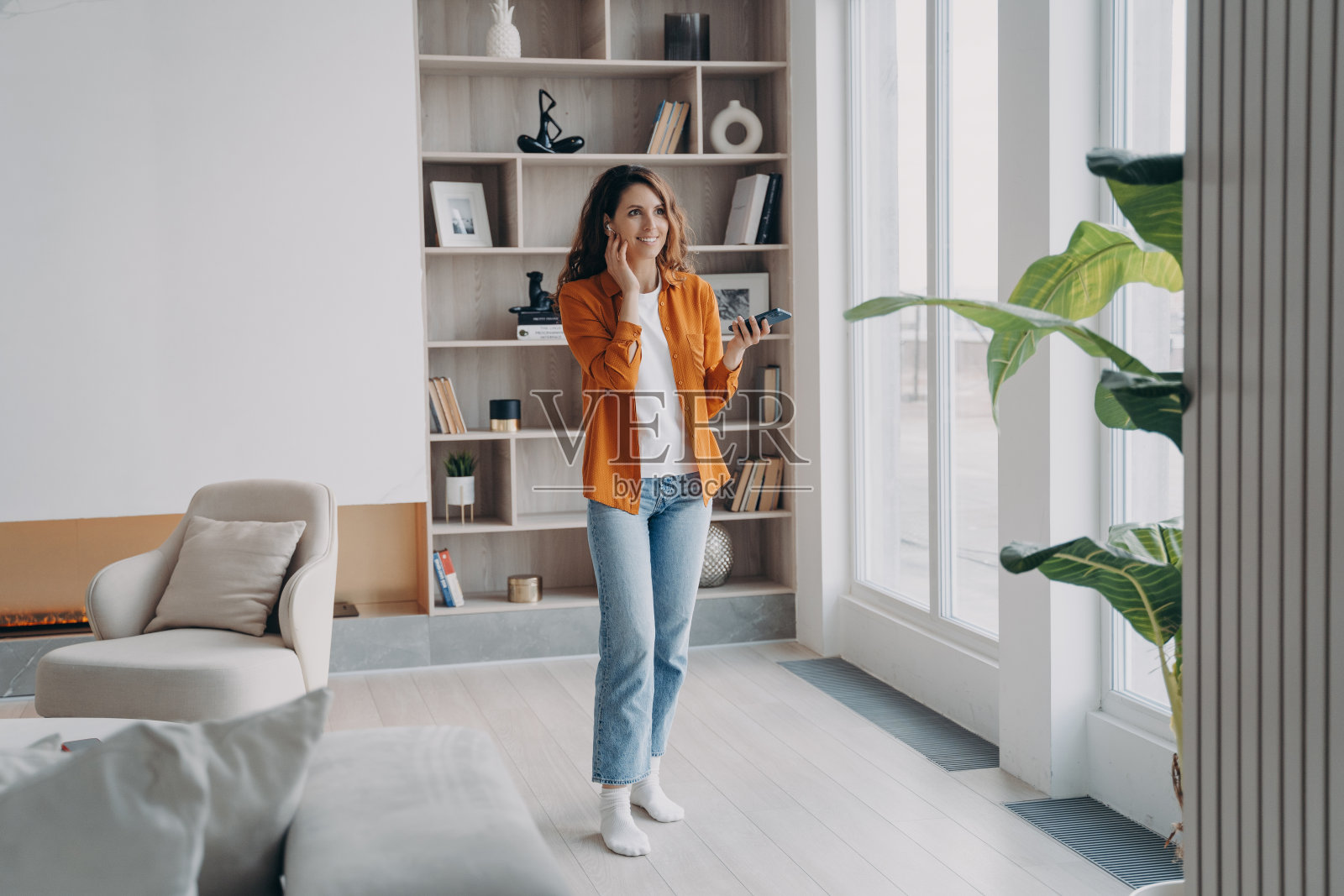 微笑的女人接听电话，在家里的现代公寓享受电话商务谈话照片摄影图片