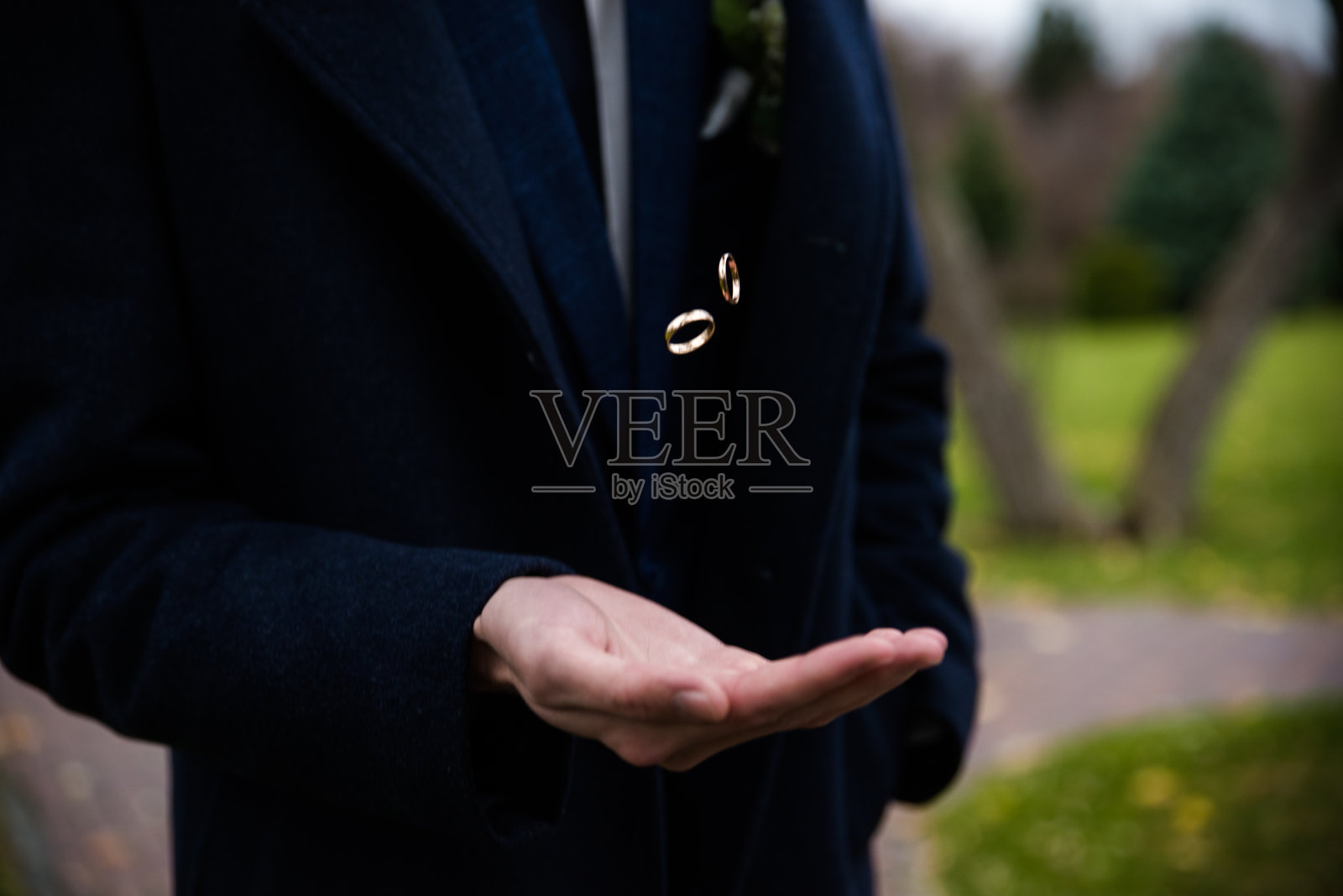 新郎手里拿着结婚戒指。地板上有两枚结婚戒指，地板上有，地上有，钢琴上有，手上有照片摄影图片