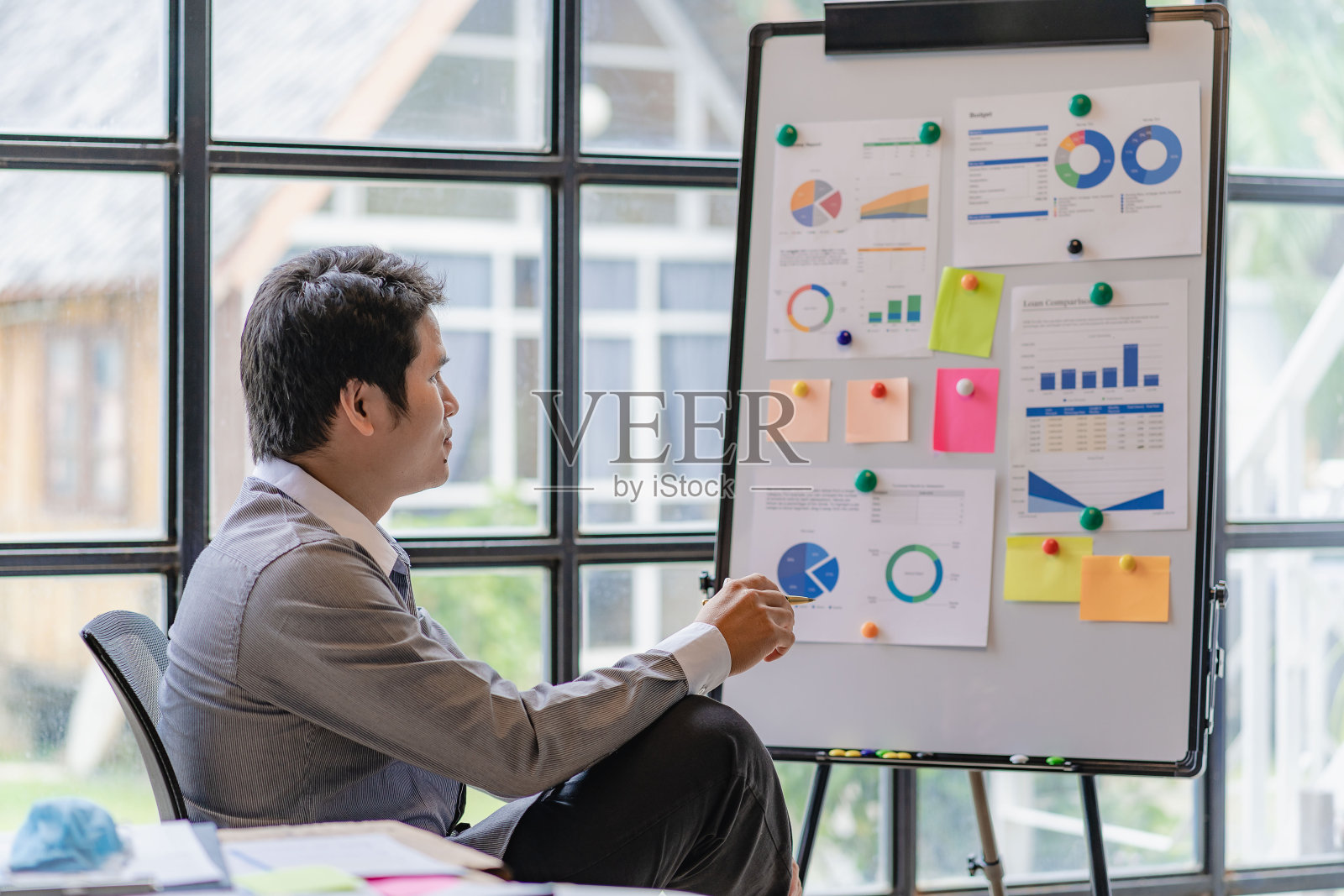 肖像亚洲男性会计工作在桌子上计算税，每年的金融文件使用计算器和笔记本电脑在工作，富有创造力的年轻亚洲商人。照片摄影图片