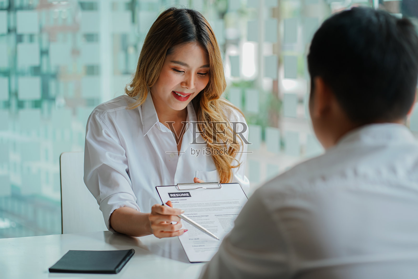 年轻人将简历交给雇主进行面试，审查工作申请这一概念表明了公司对工作岗位、员工达成一致的能力。照片摄影图片