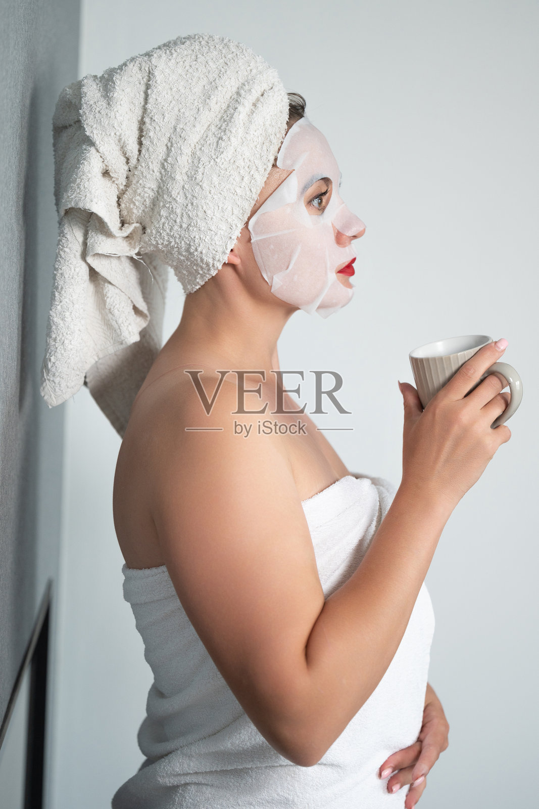 面部护理，一个女孩和一个织物面膜在她的脸上。照片摄影图片