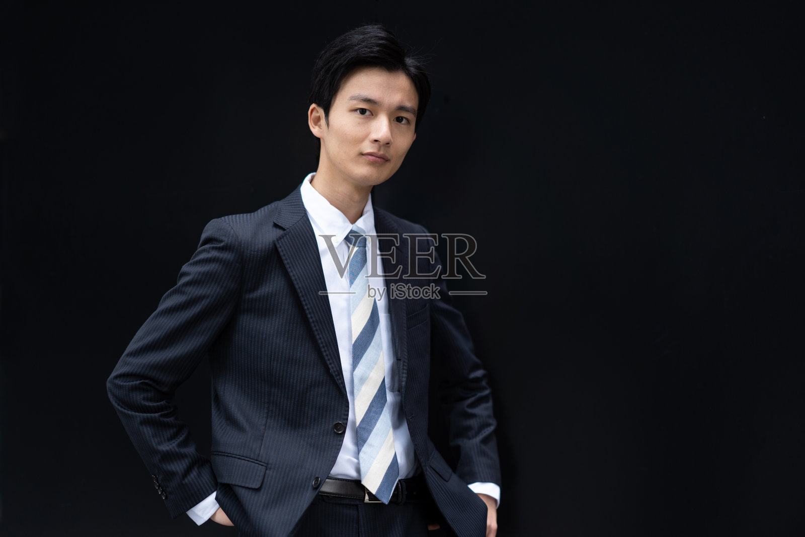 一个日本商人的肖像对着一堵黑色的墙照片摄影图片