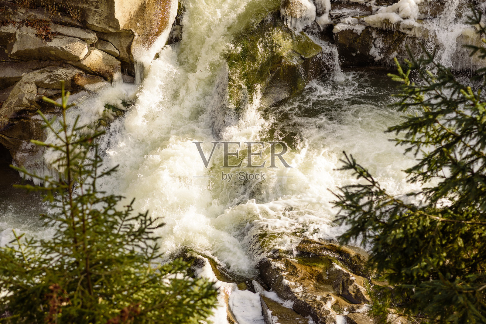 在美丽的冬季山区河流上，山坡上的针叶林郁郁葱葱照片摄影图片