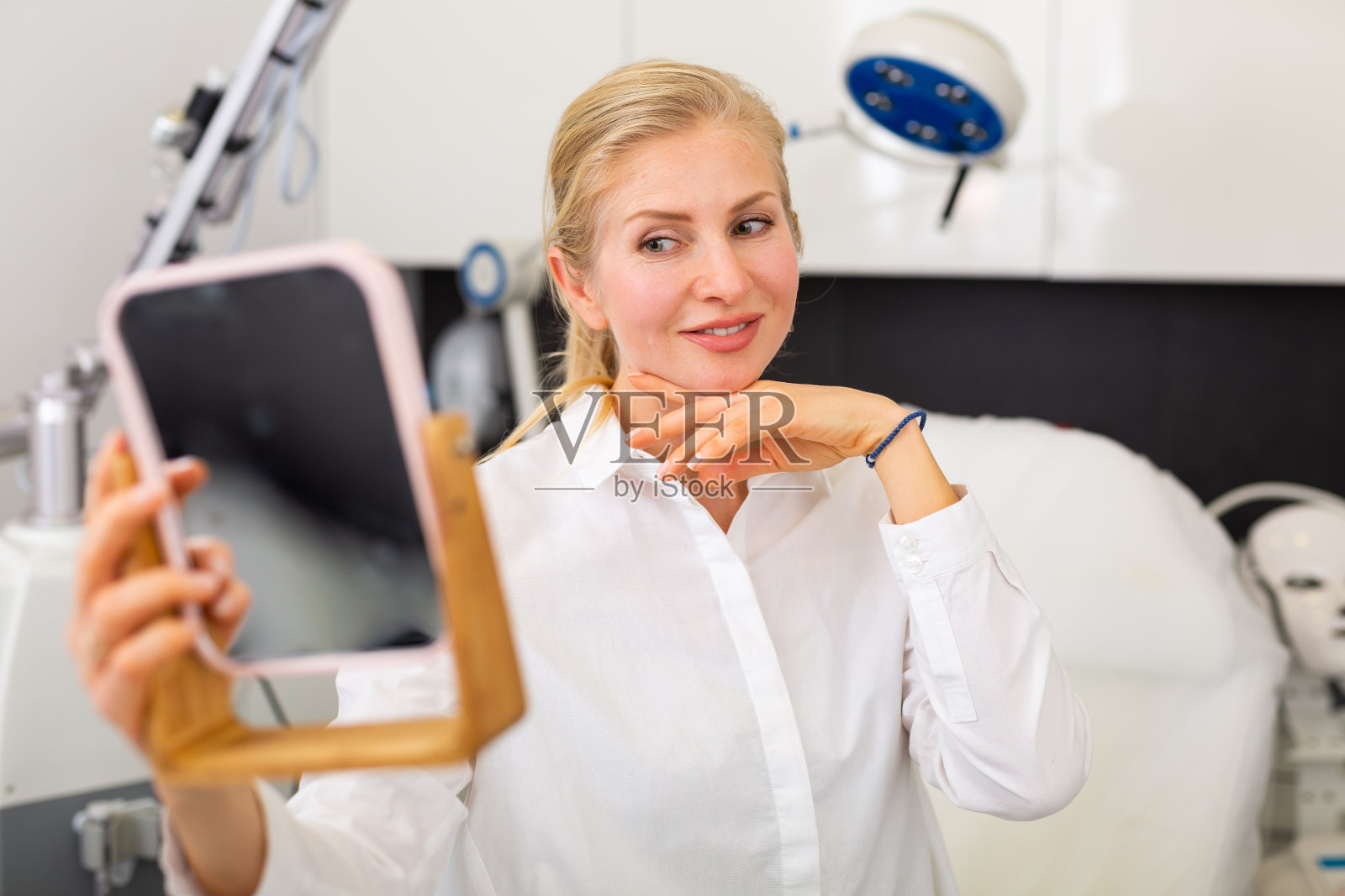 女人在整容手术后看着自己的倒影照片摄影图片