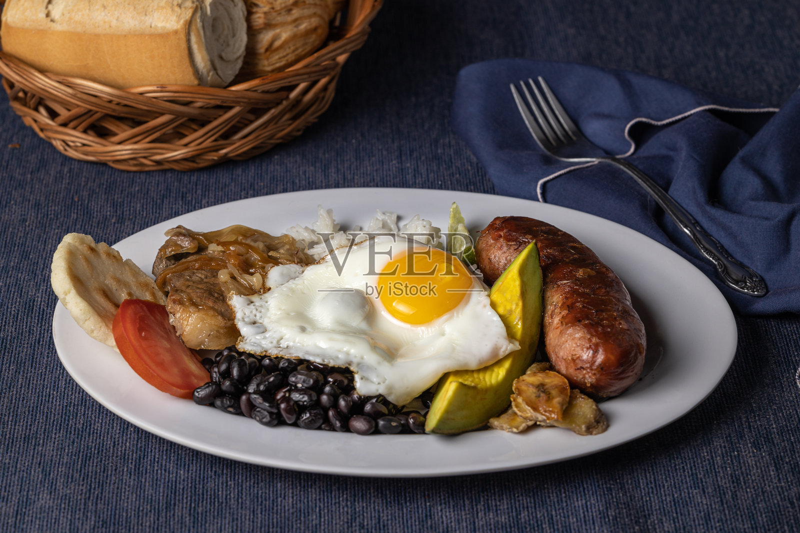 Bandeja paisa，哥伦比亚的典型食物，放在蓝色桌布上。照片摄影图片