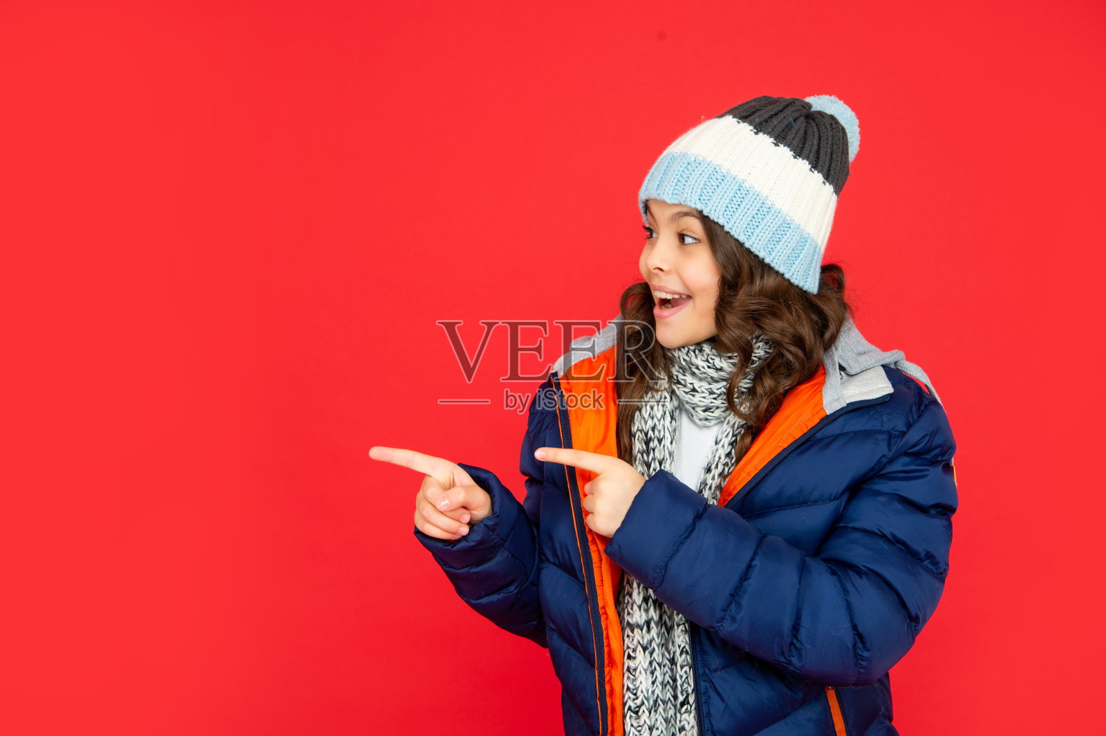 表达积极的情绪。冬天的时尚。将手指指向复制空间。惊讶的孩子照片摄影图片