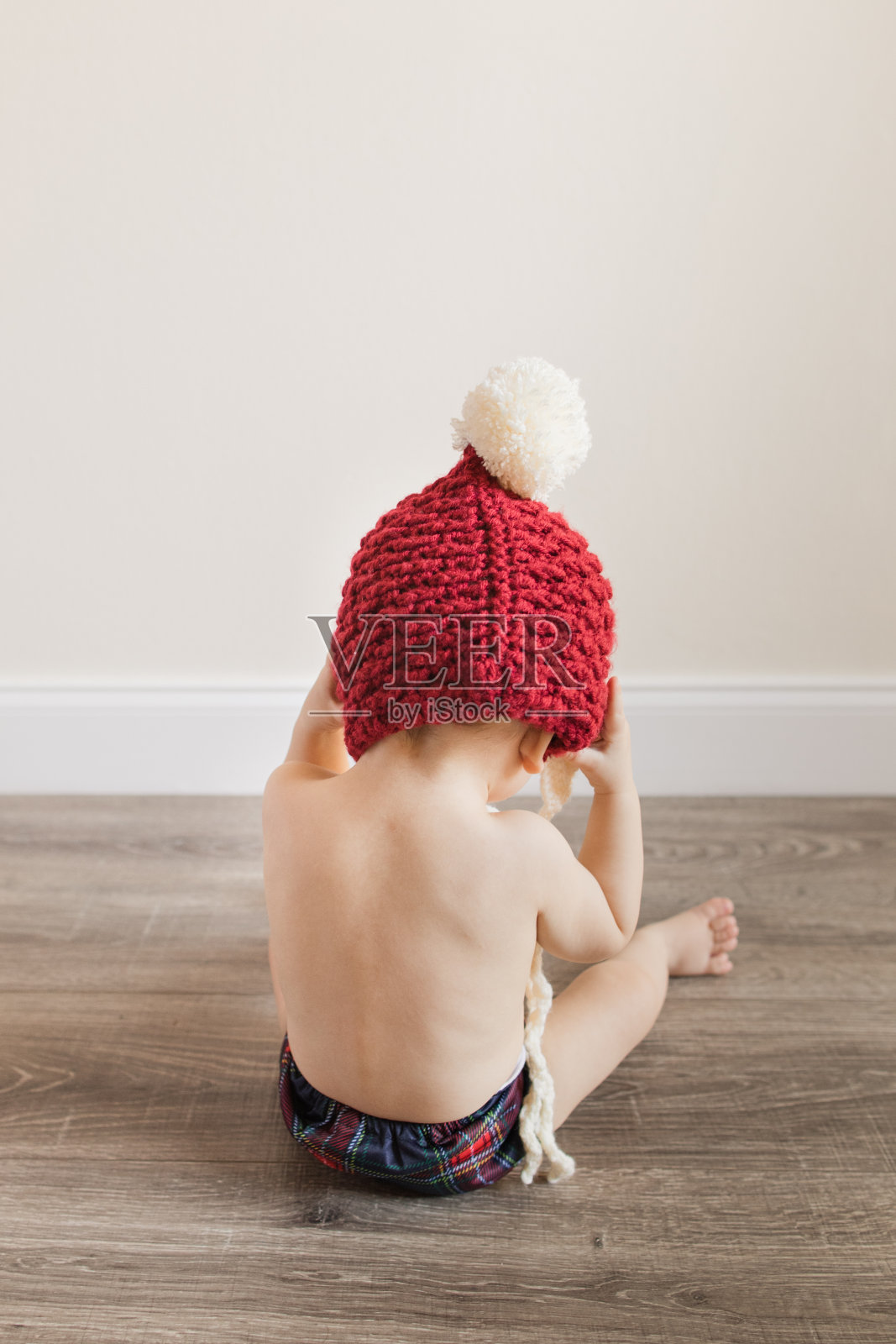 一个11个月大的圣诞男婴，有12只脚趾，穿着可持续的圣诞布尿布，坐在木地板上玩圣诞礼物，为他的生日和2022年的假期做准备照片摄影图片