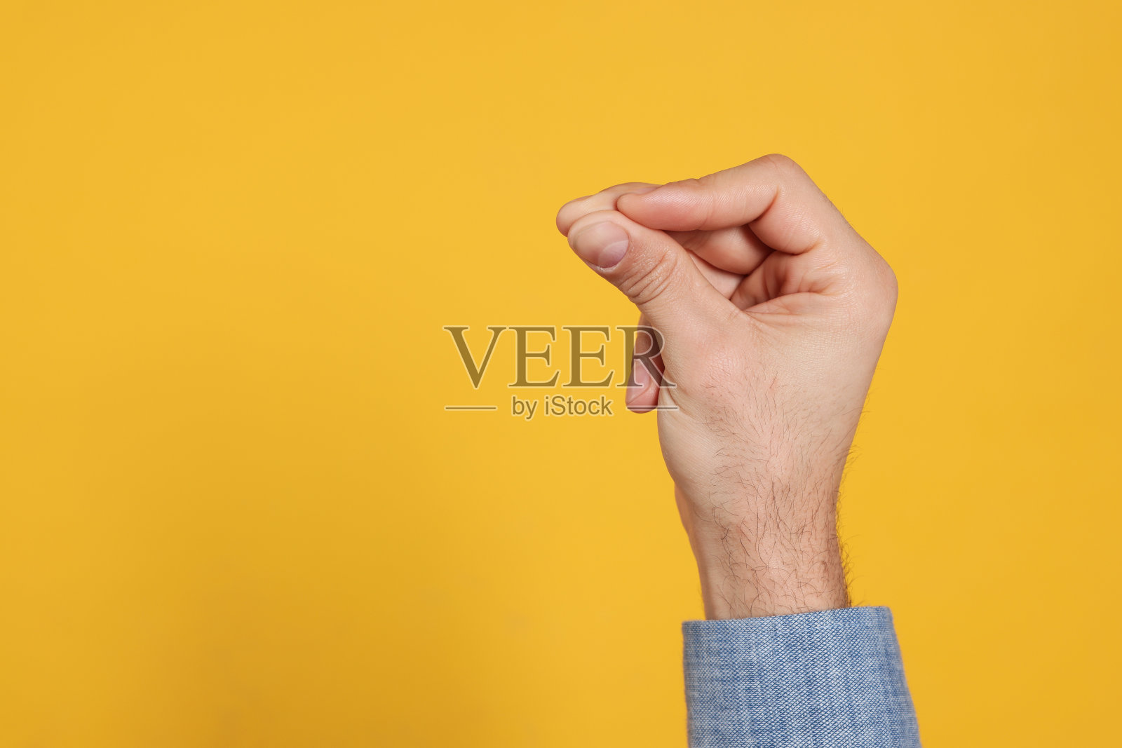 男子在黄色背景上打响指，手部特写。文本空间照片摄影图片