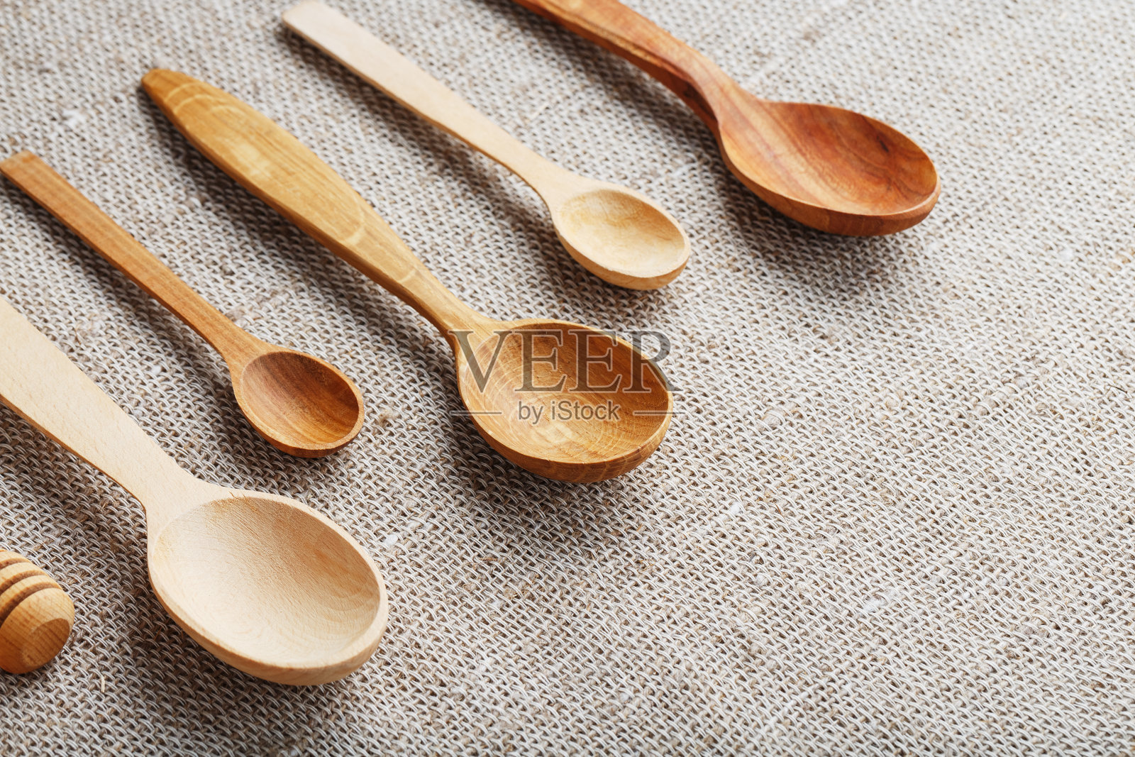 由不同类型的木材制成的工艺勺子在麻麻布上排成一排。俯视图，空闲空间照片摄影图片