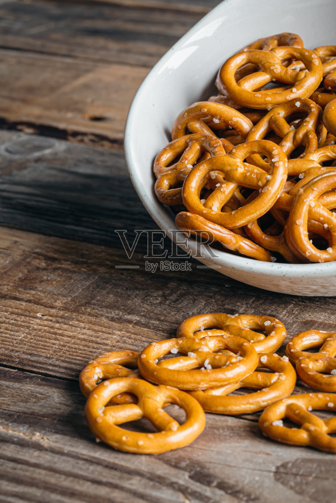 咸的迷你派对椒盐卷饼在一个碗上的木质表面特写。照片摄影图片