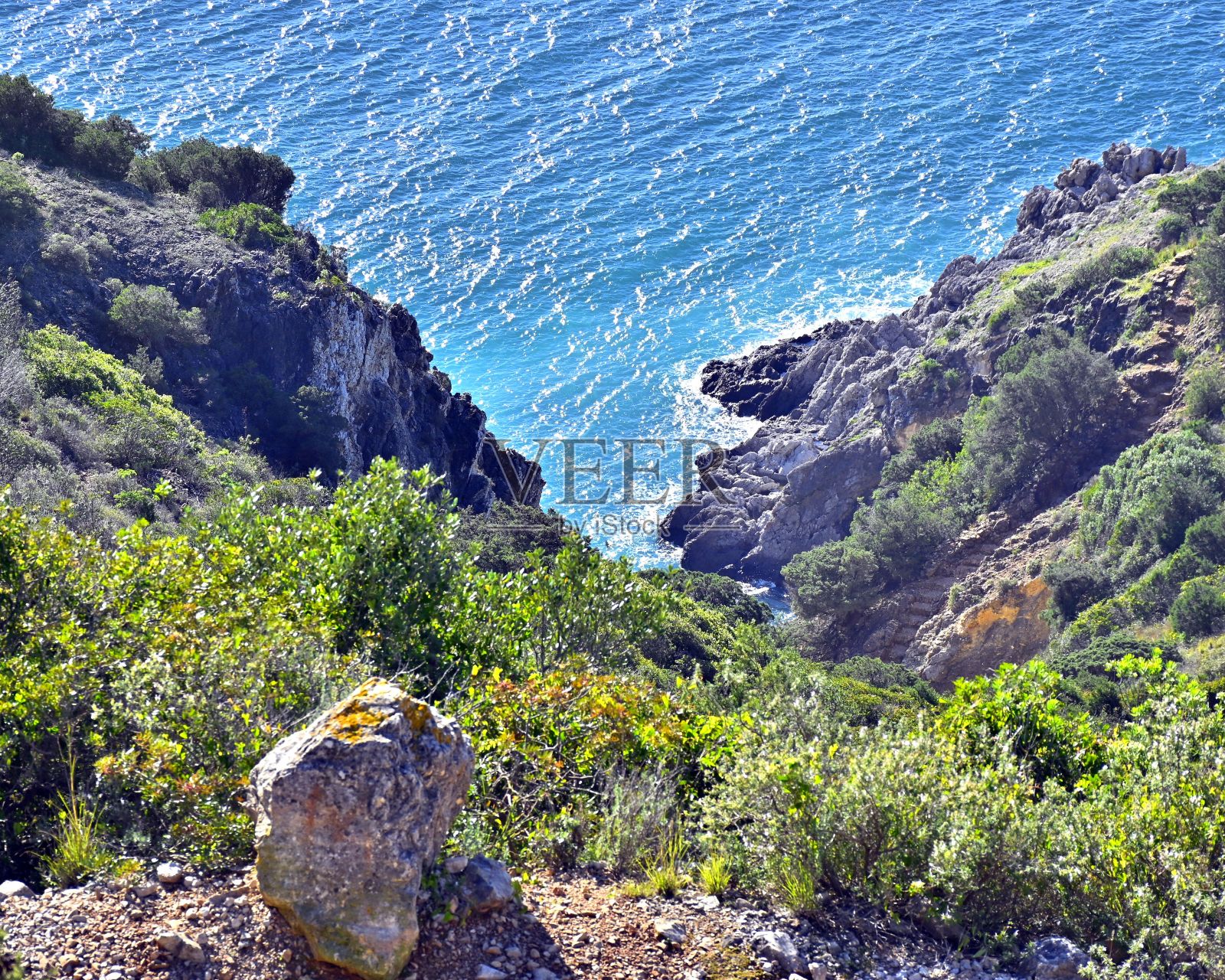 葡萄牙的普拉亚达米约纳海滩和蓝天下被岩石山丘包围的蓝色大海照片摄影图片