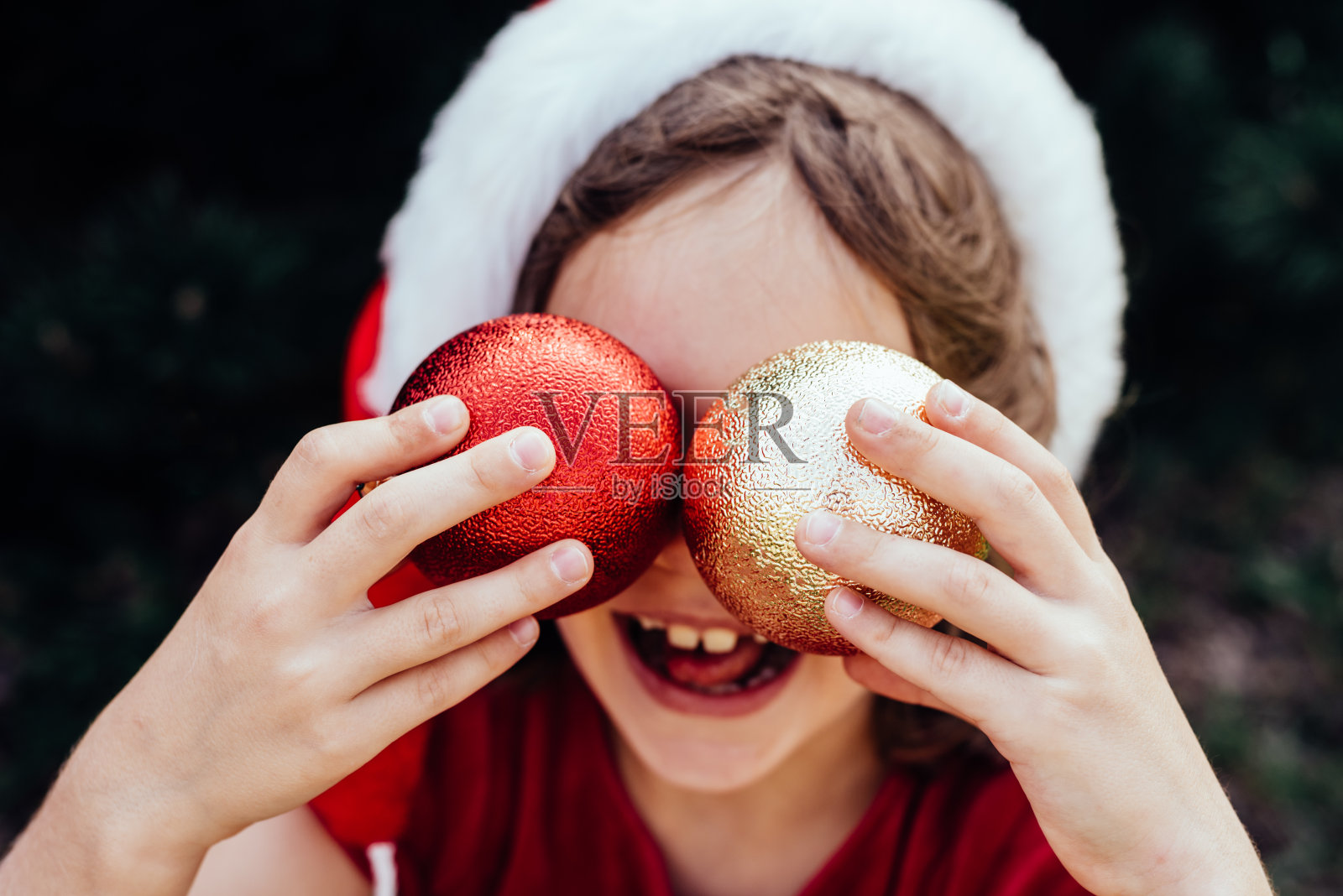 圣诞快乐。快乐有趣的孩子女孩的肖像在圣诞帽与圣诞花环。照片摄影图片