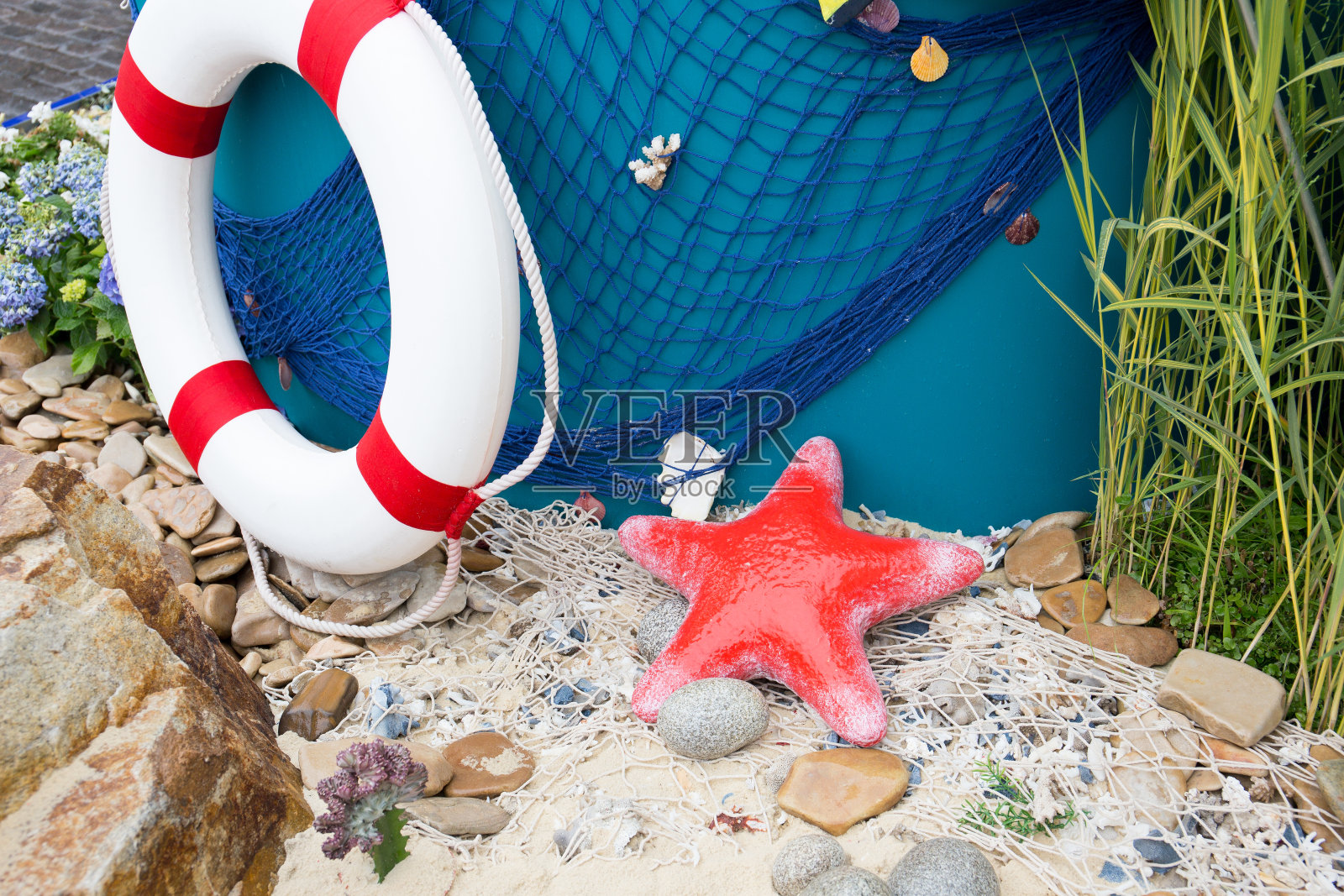 海沙和红海星渔网，海卵石，生命线和贝壳特写。照片摄影图片