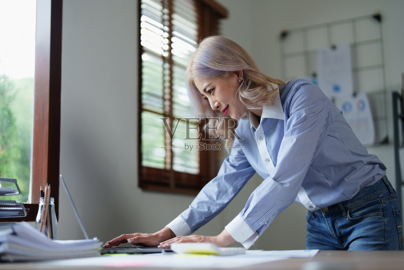 一个深思熟虑的亚洲女商人的肖像看着财务报表和制定营销计划使用电脑在她的桌子上照片摄影图片