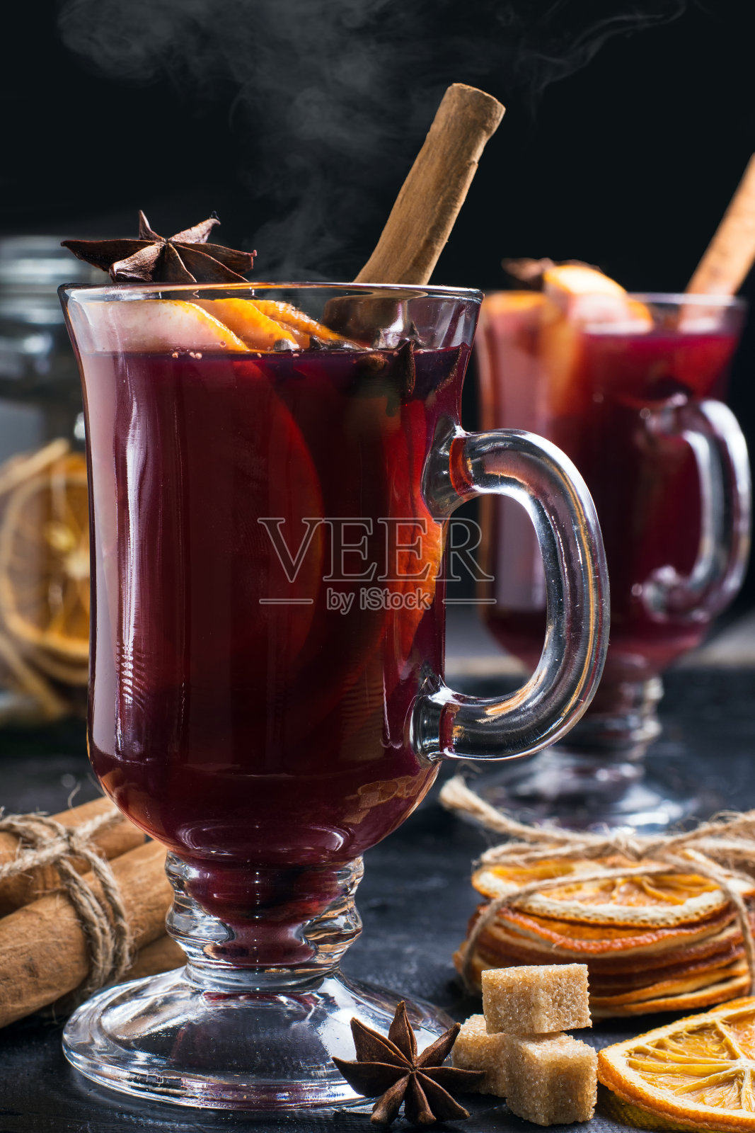 以肉桂和八角星为背景的黑色玻璃杯，热气腾腾的热葡萄酒。冬天的酒精鸡尾酒。圣诞传统饮品照片摄影图片
