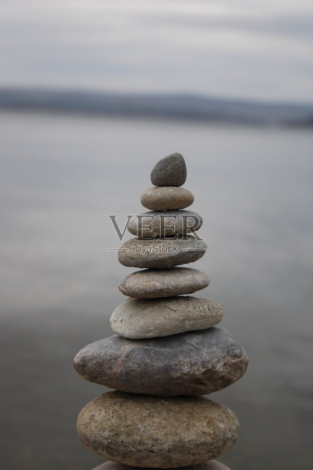 海滩上的一堆石头。海滩上各种各样的石头。石塔，土地艺术，装置，石头。石头保持平衡。正念主题的照片。照片摄影图片