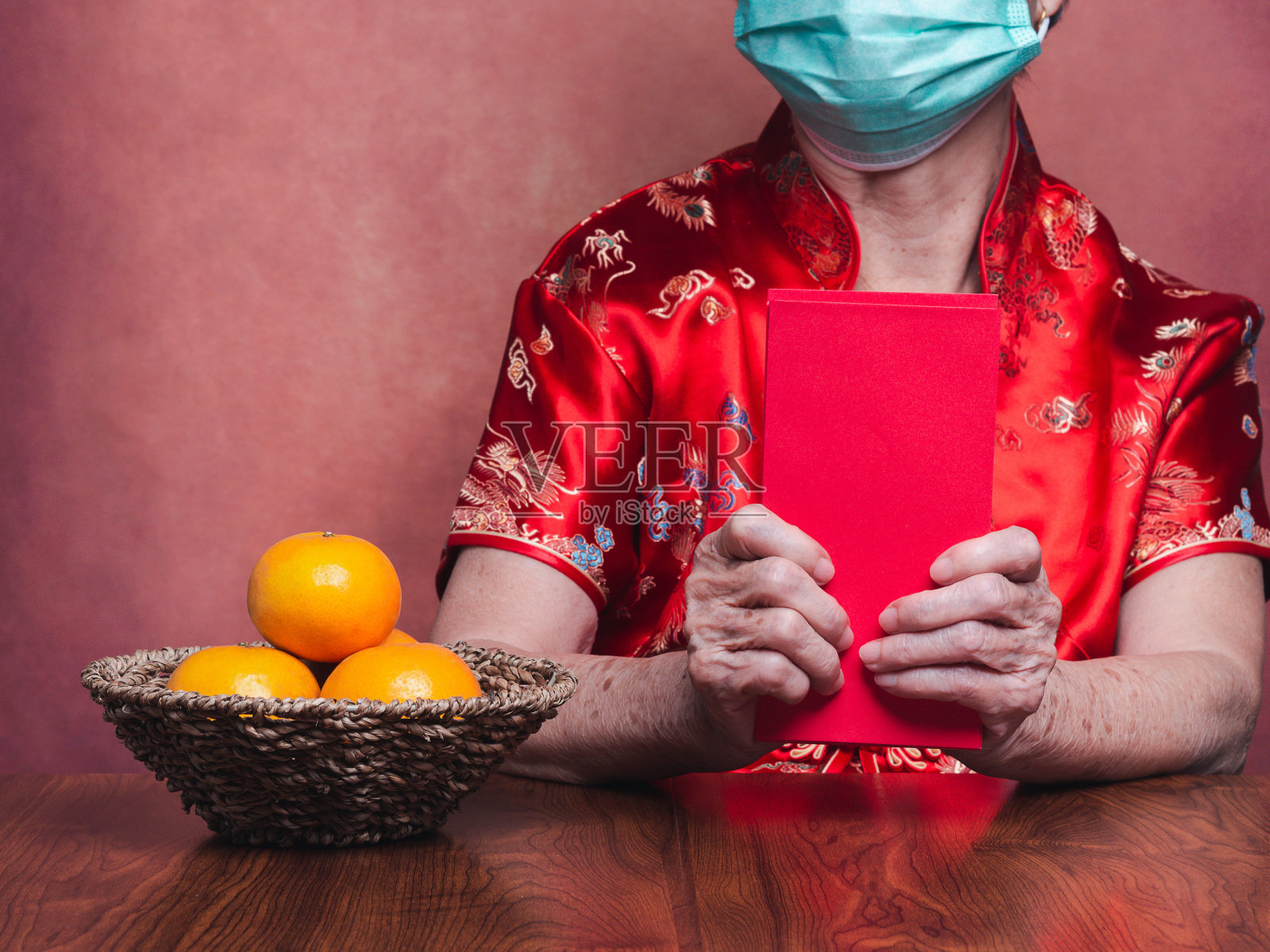手持红包或身着传统旗袍，戴着口罩坐在演播室的妇女的手照片摄影图片