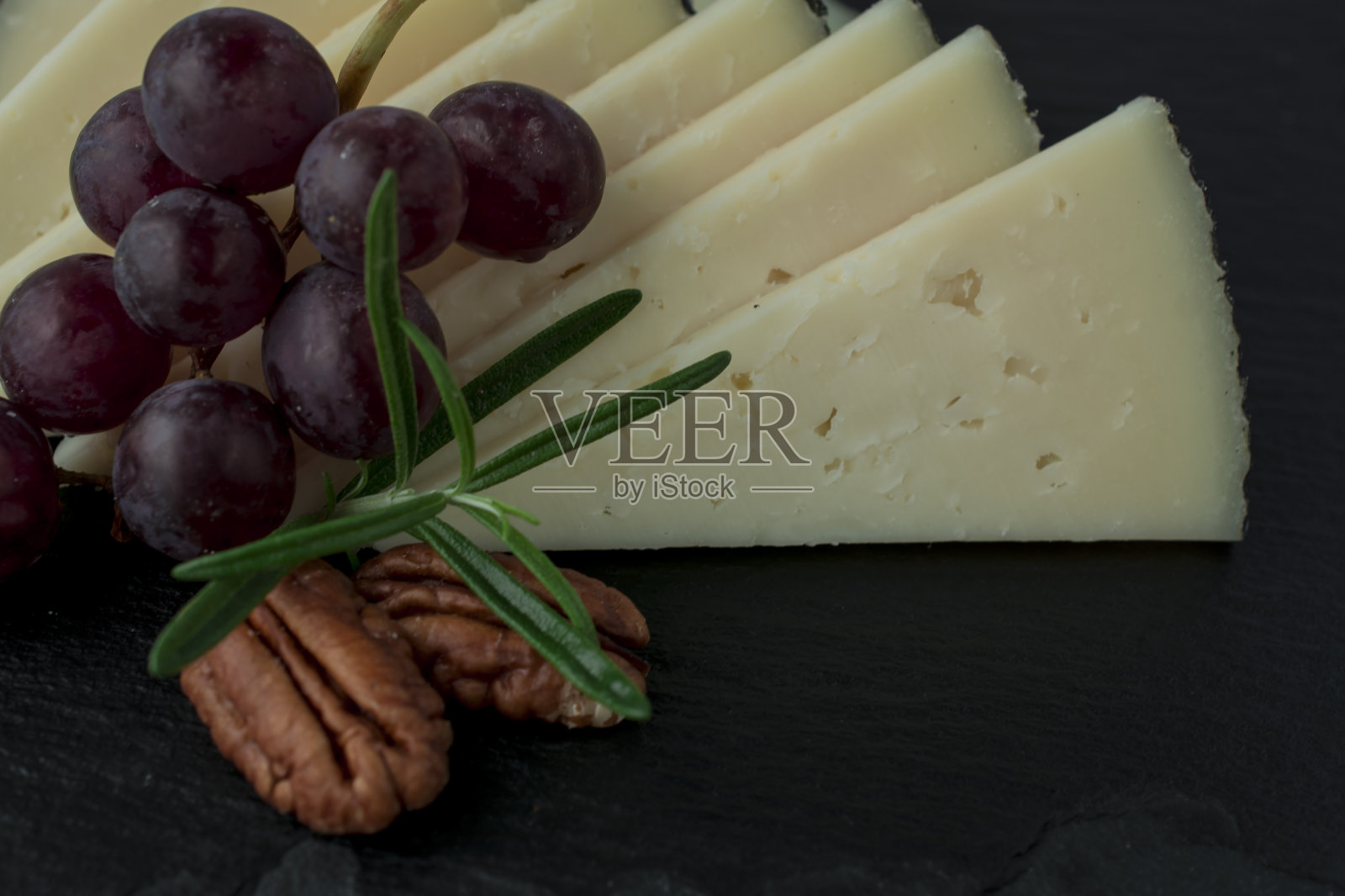 葡萄，坚果，山羊奶酪。木板。照片摄影图片