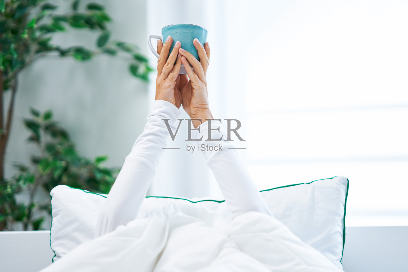 年轻漂亮的女人在床上咖啡或茶杯照片摄影图片