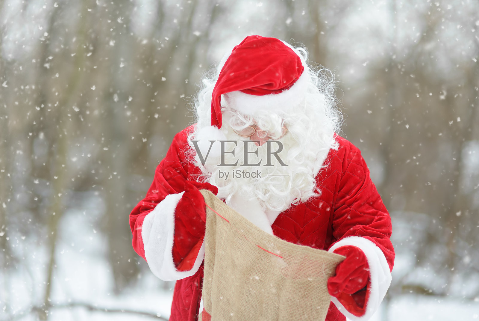 圣诞老人从袋子里拿出圣诞礼物。圣诞老人在孩子们的节日里穿着圣诞老人服装的动画师或父母圣尼古拉斯节。照片摄影图片