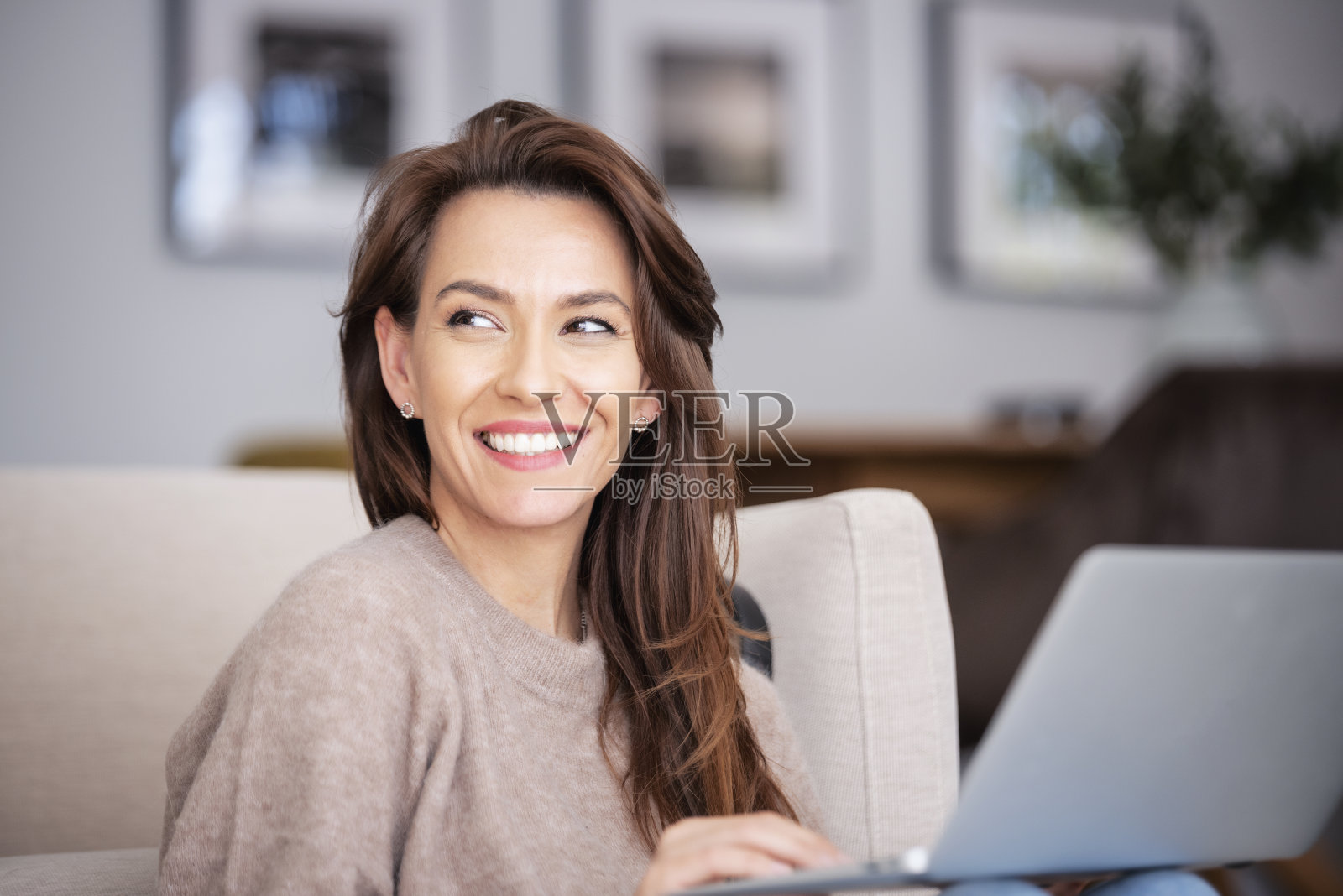 微笑的白人妇女在家里使用笔记本电脑，而坐在地板上照片摄影图片